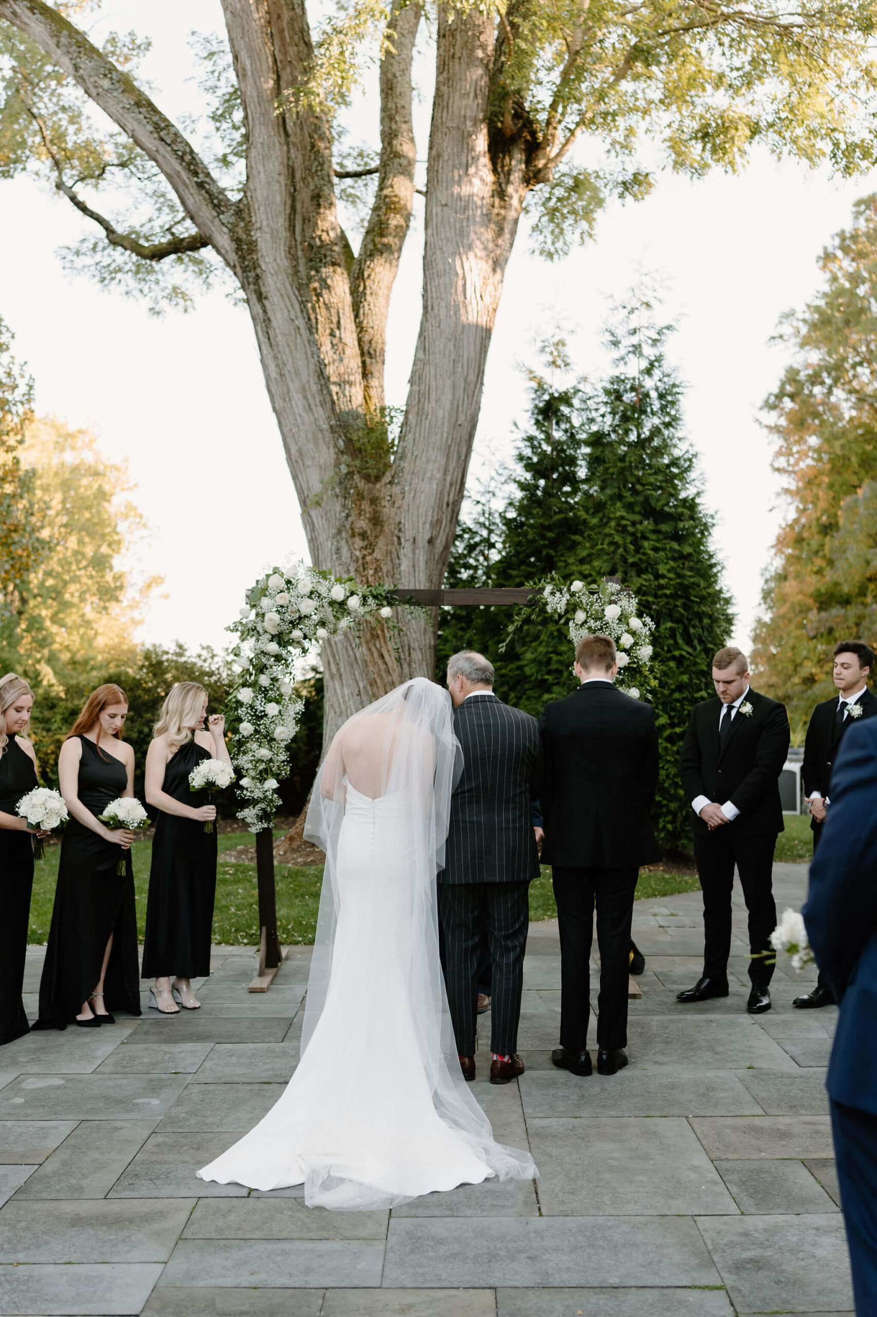 groom walking bride up to the altar, leaning his head together with hers during prayer, groom's head bowed beside them