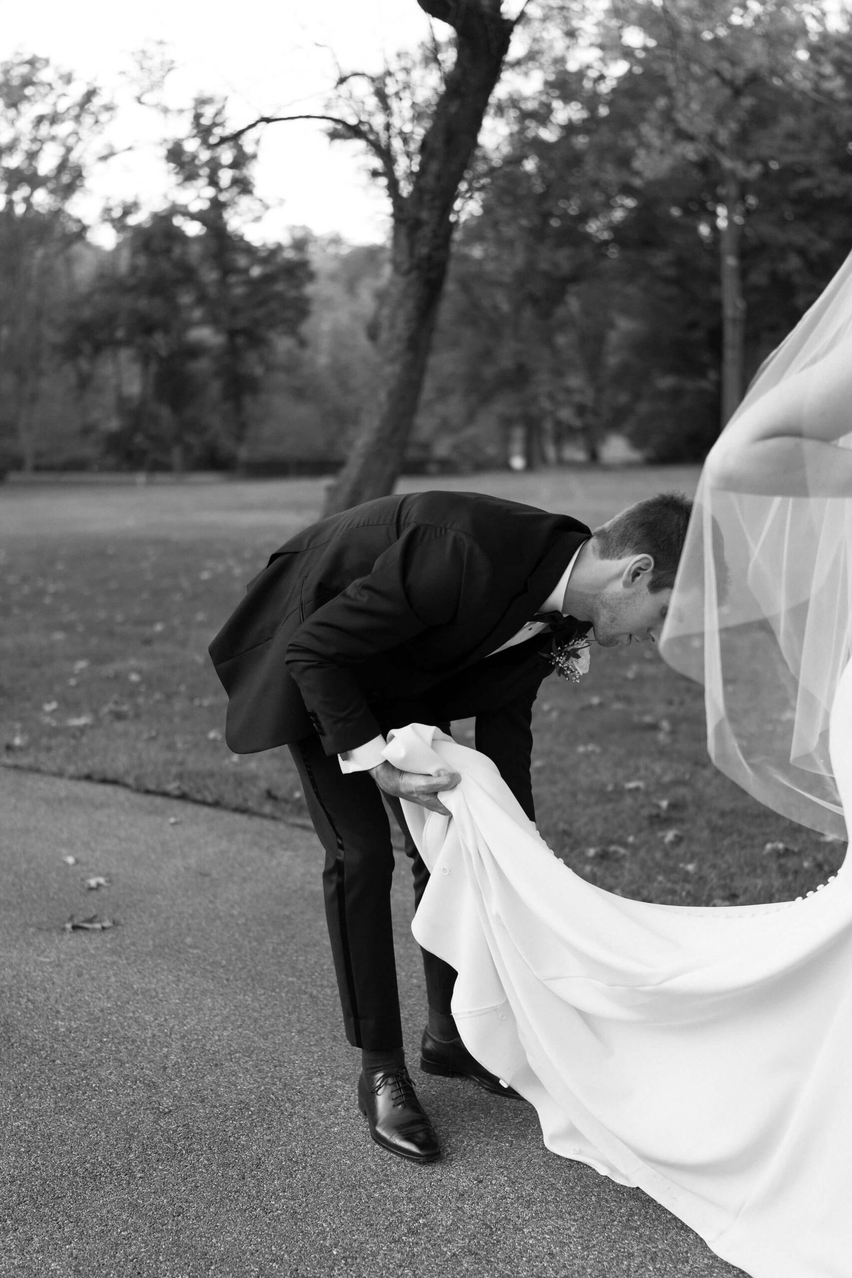 Groom arranging the train of his bride's wedding gown