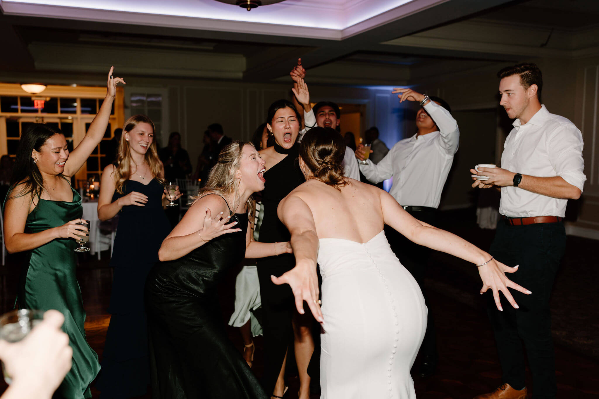 bride with her hands out wide beside her, sing-screaming toward her friends on the dance floor at her wedding reception at Radnor Valley Country Club