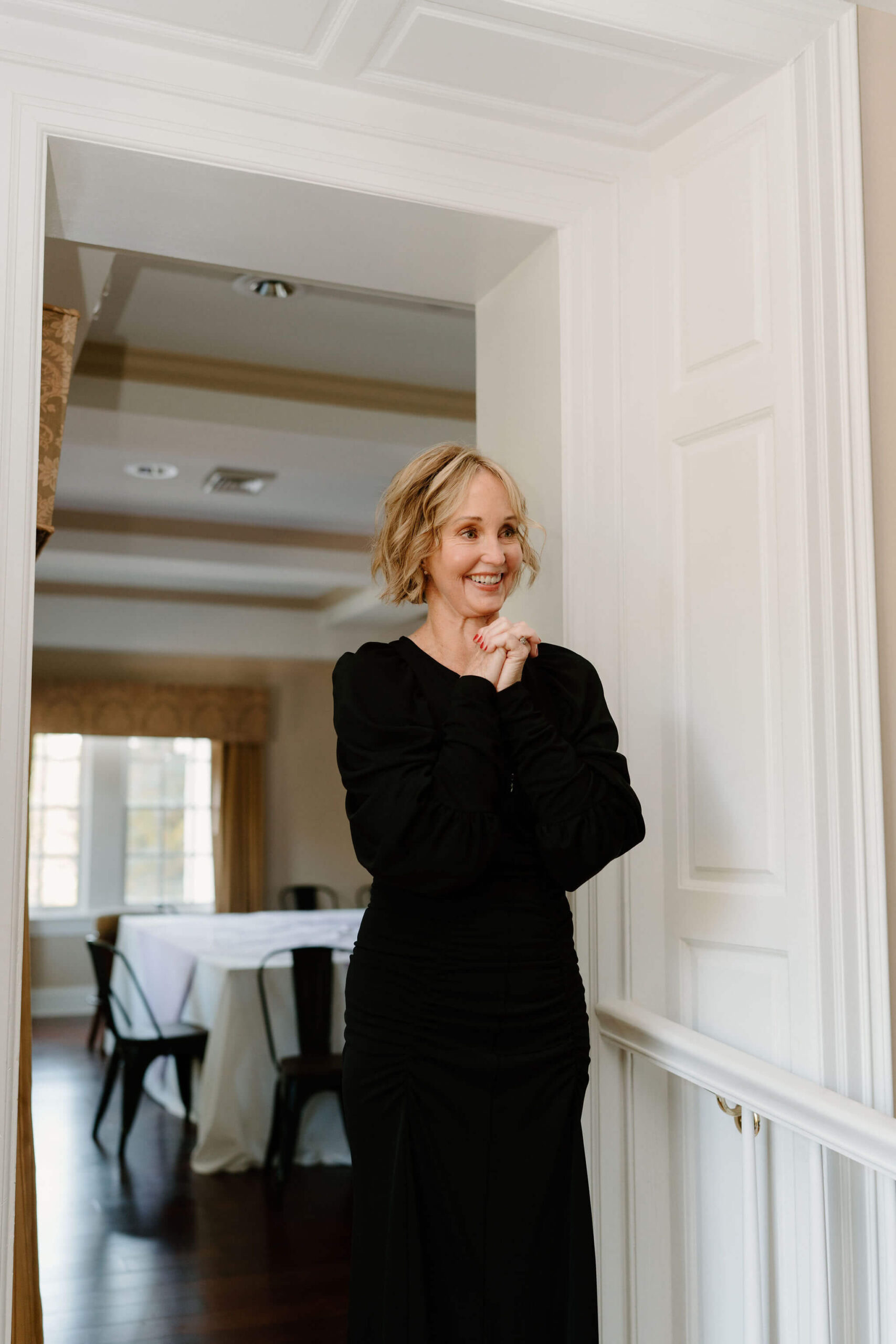 mother of the bride smiling off camera, hands clasped at her heart, tears in her eyes