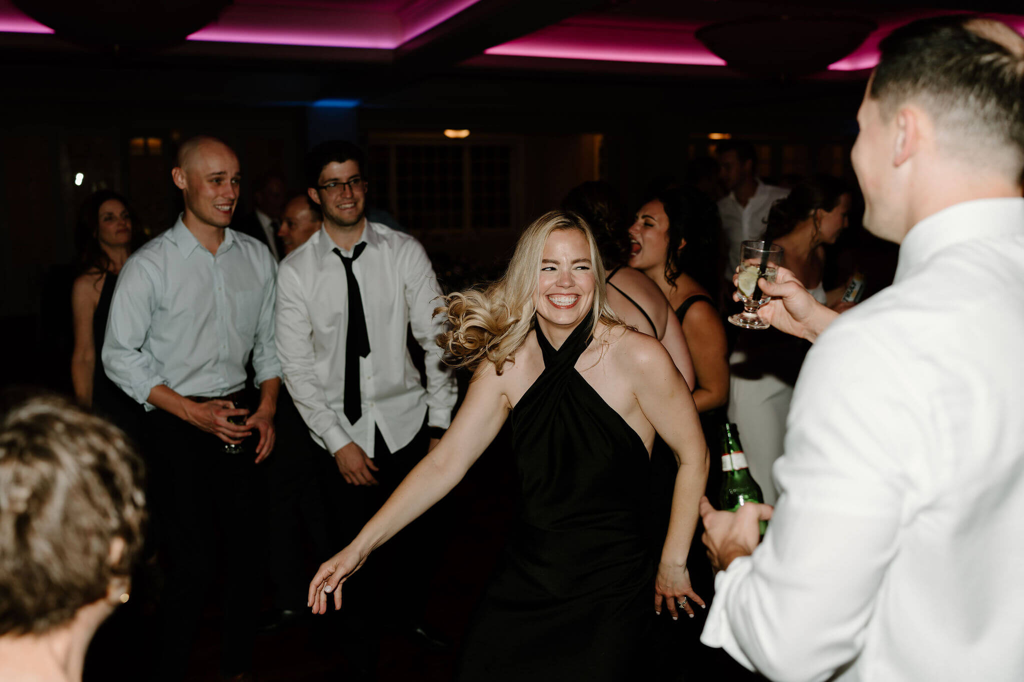 bride's sister dancing and smiling widely on the dance floor at her wedding reception