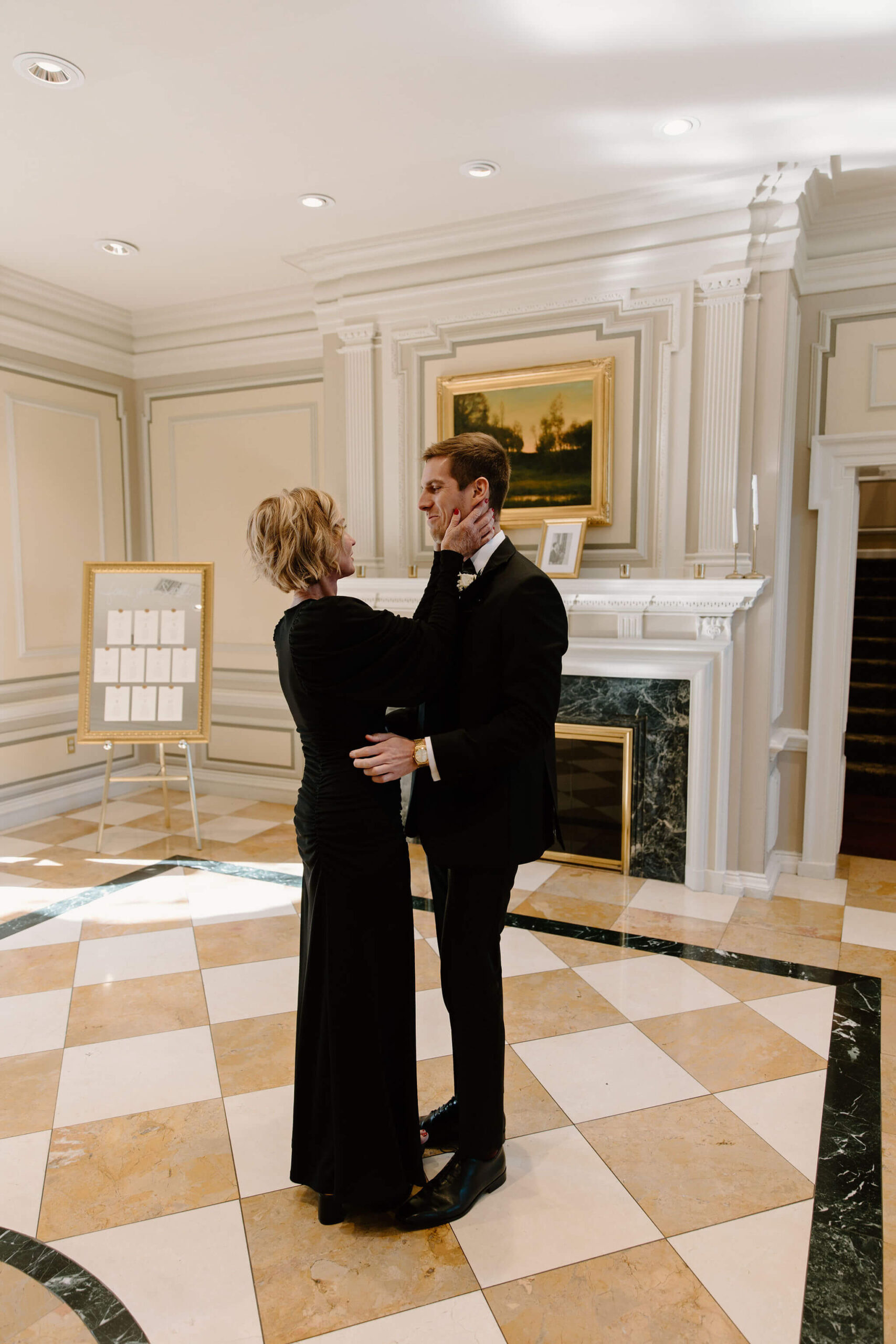 mother of the bride holding the groom's face and hugging him