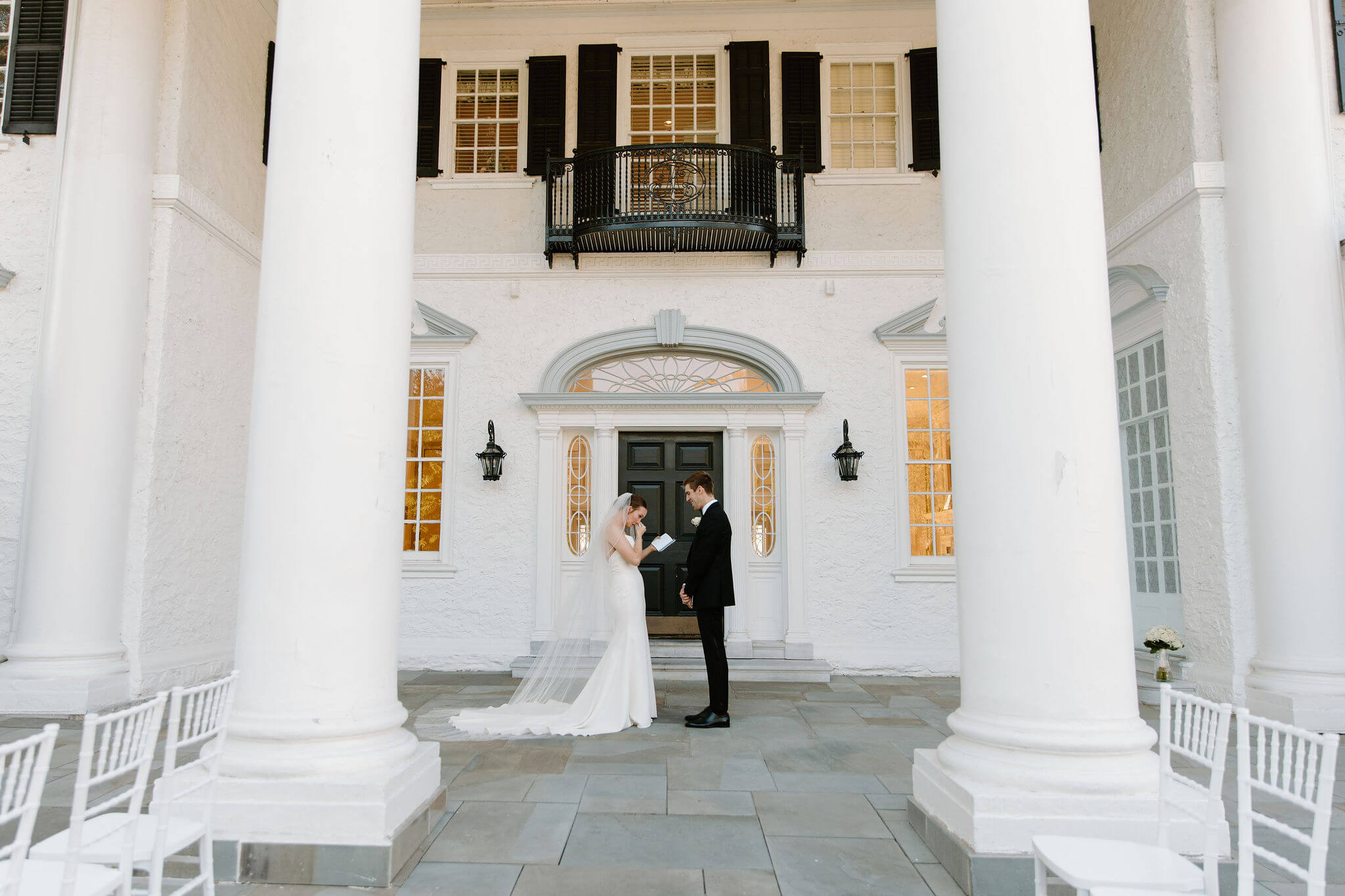 bride (white open back wedding gown, cathedral length veil) and groom (black suit) exchanging wedding vows privately in front of the Radnor Valley Country Club clubhouse