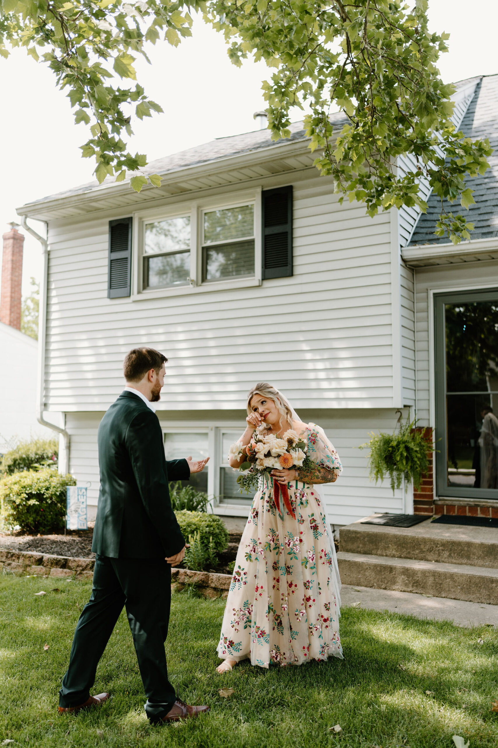 bride in a colorful embroidered wedding dress wiping tears from her eyes as she sees her husband for the first time on their wedding day
