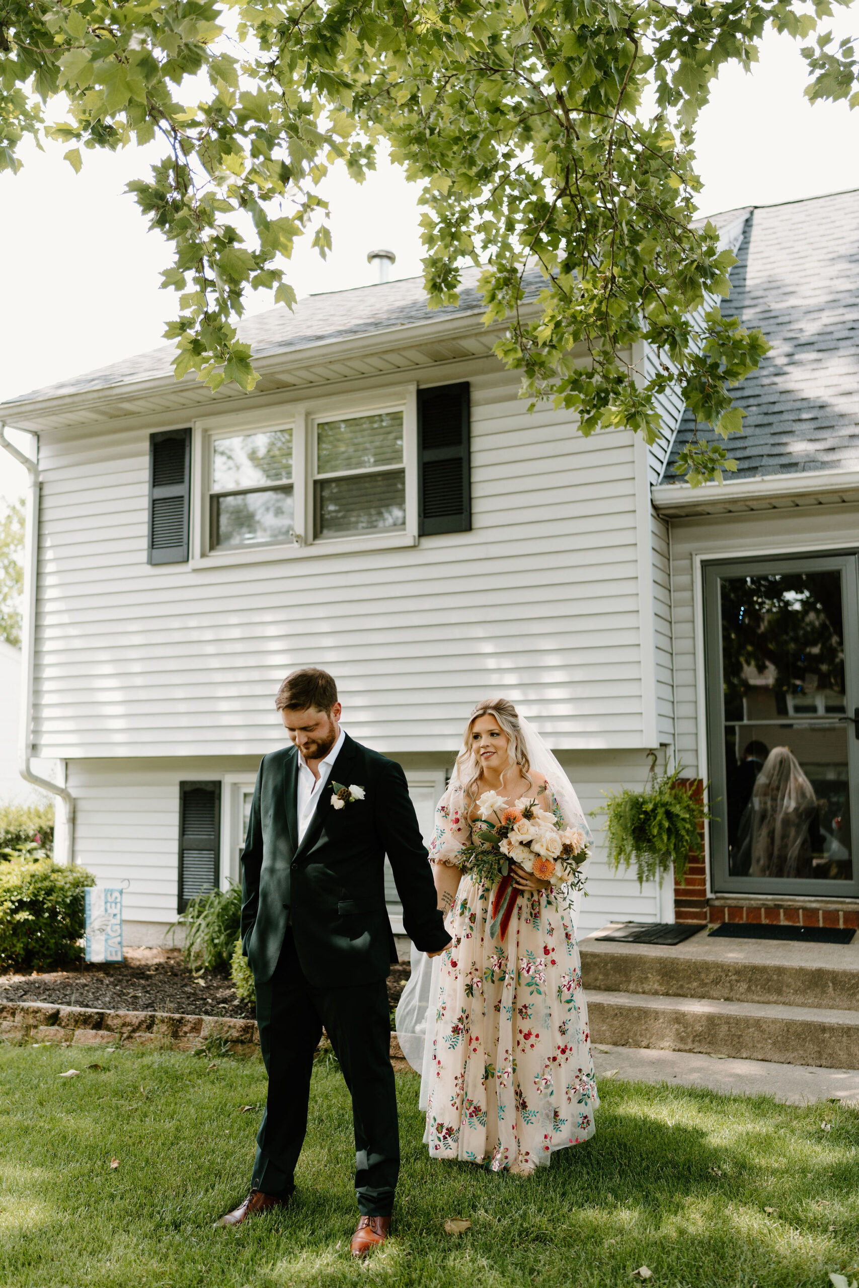 bride in a colorful wedding dress approaching groom for their first look on their wedding day, reaching out to hold his hand while his back is to her