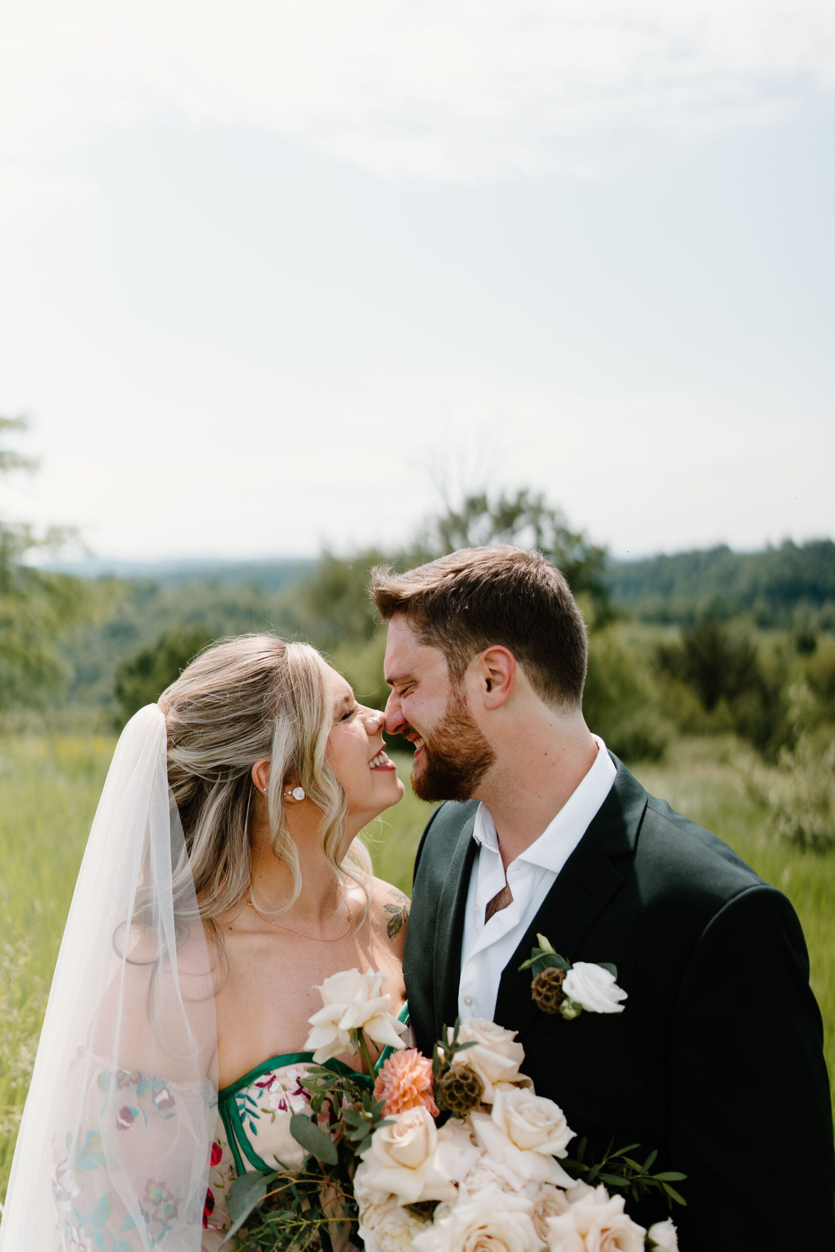bride with curled hair smiling at groom as they go in for a kiss