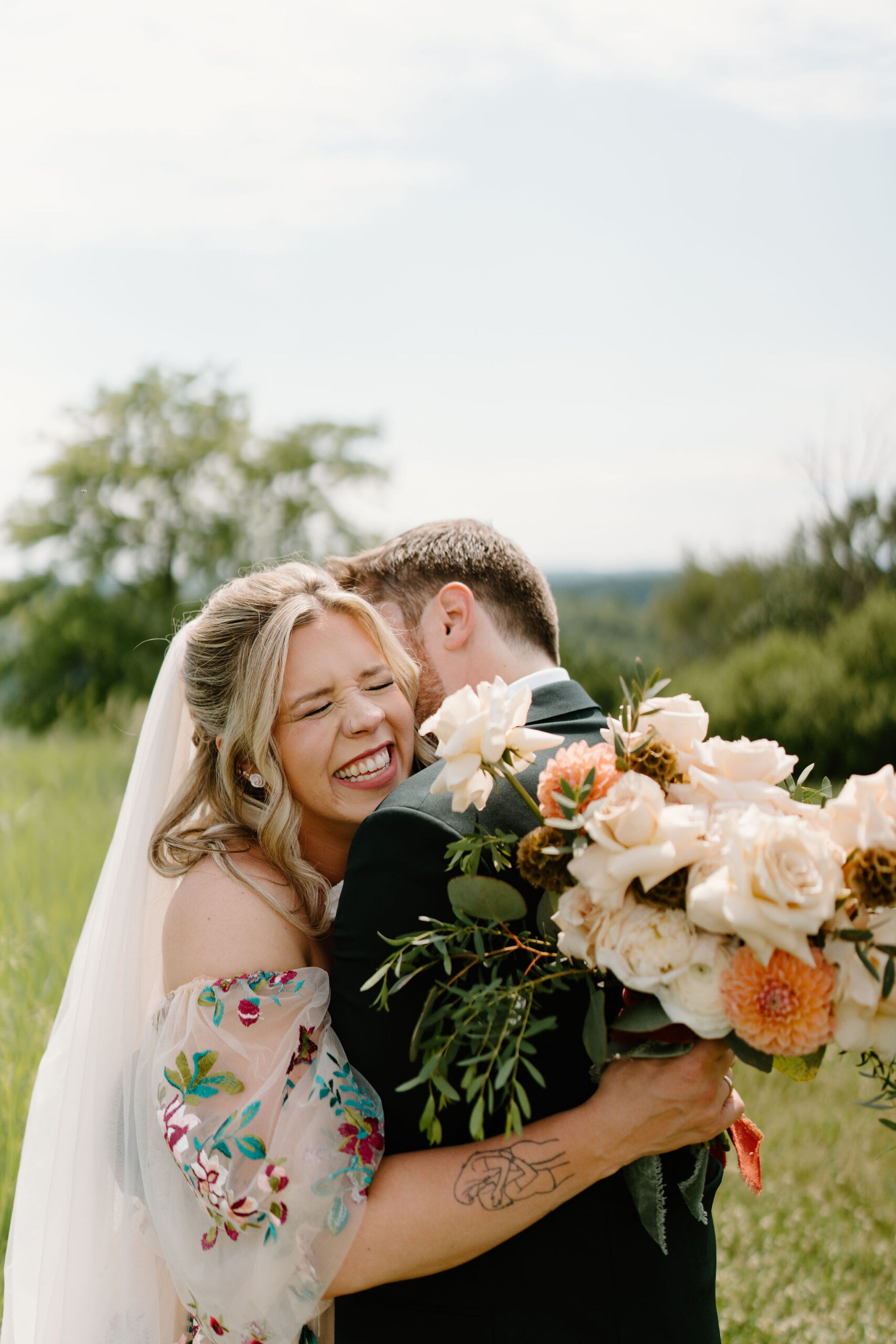 bride laughing and smiling as her groom kisses her on the cheek on their wedding day