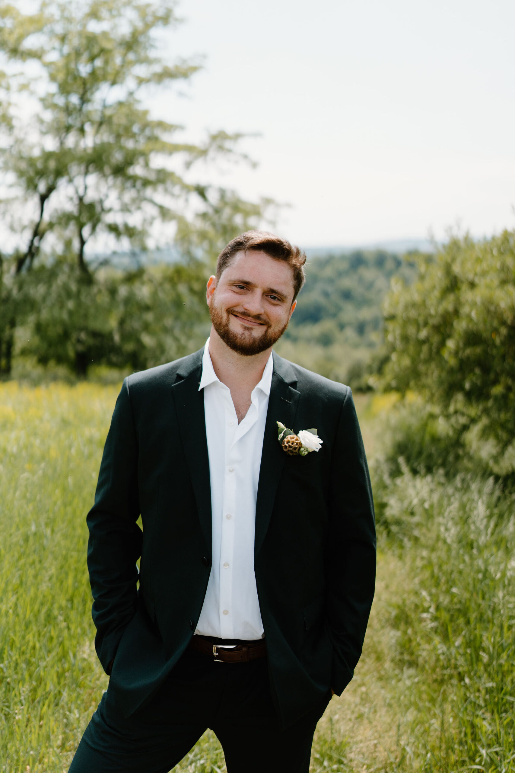 groom with his hands in his pockets, smiling at the camera