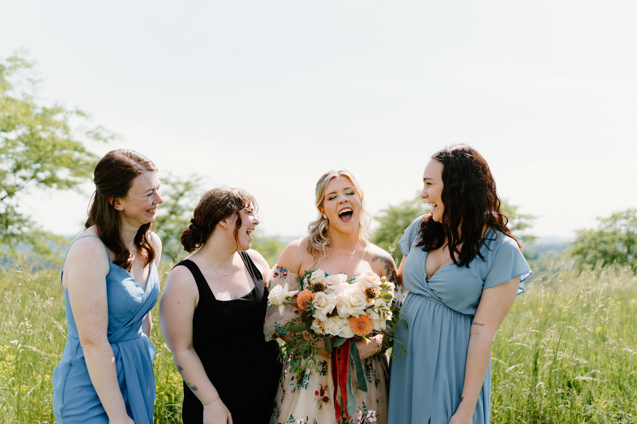 bride in a colorful wedding dress laughing and smiling with three of her friends and bridesmaids