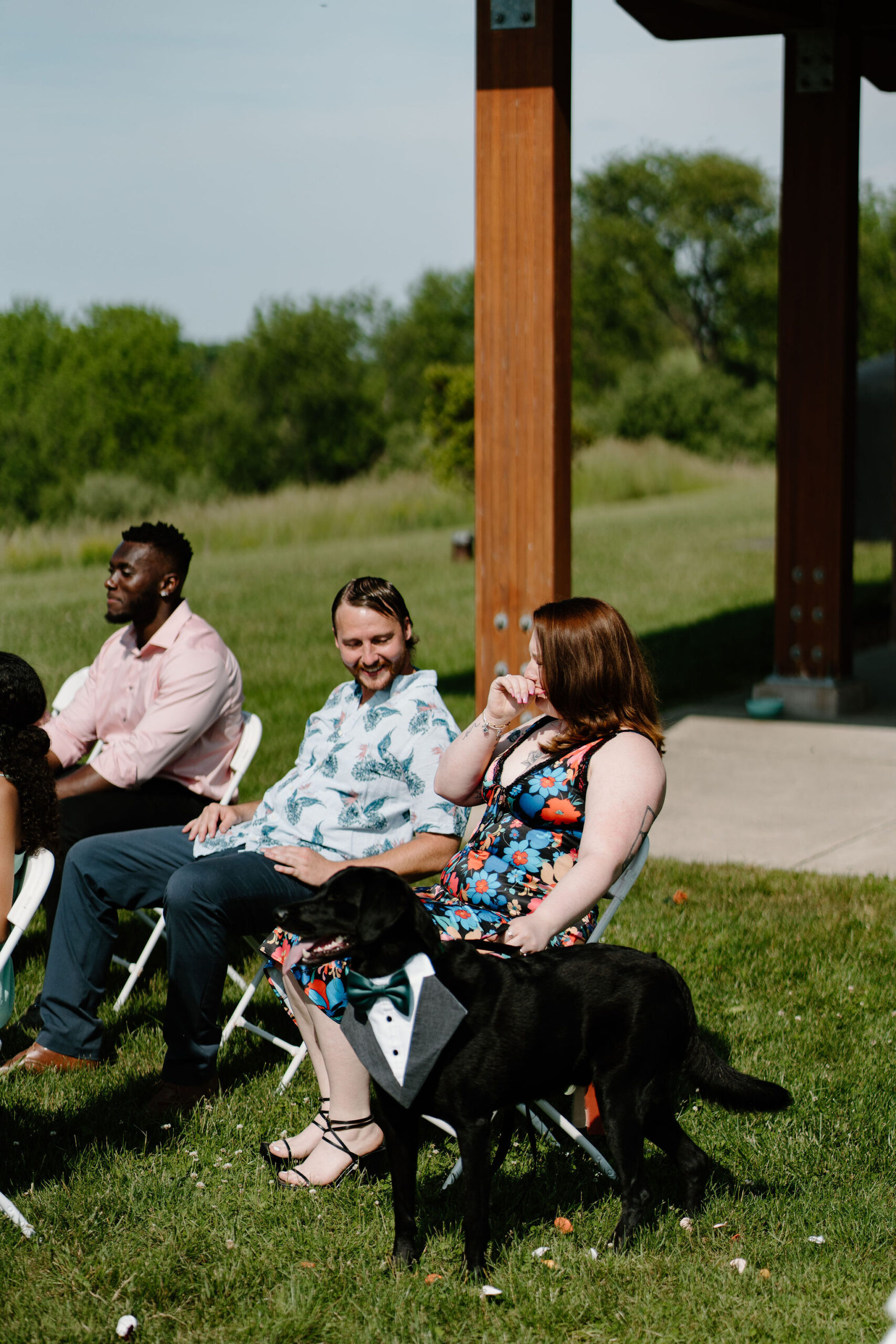 sister of the bride sitting in her chair, holding one of their dogs, while crying during the wedding ceremony