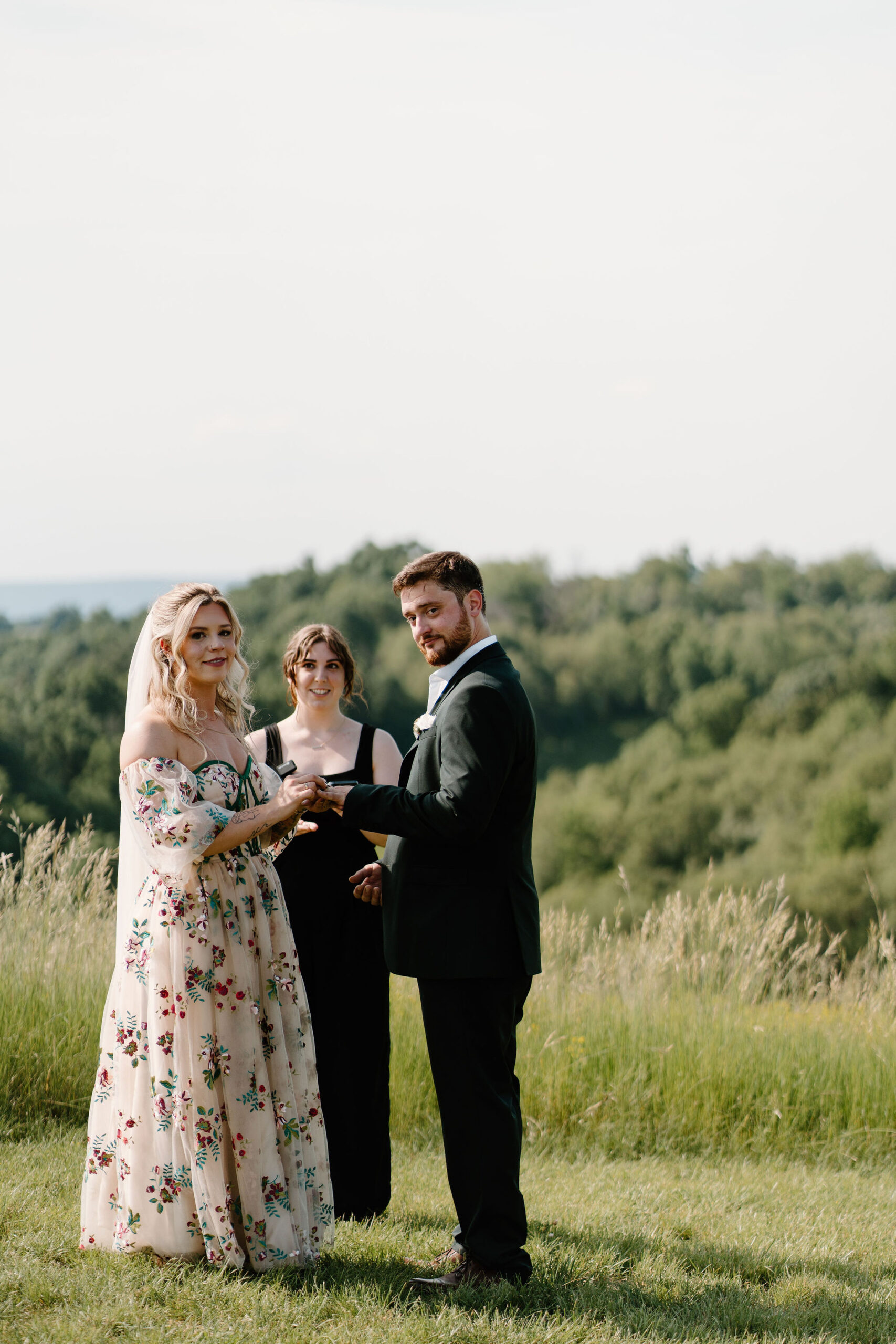 intentionally awkward image of bride and groom putting their rings on each other during their wedding ceremony and staring directly at the camera