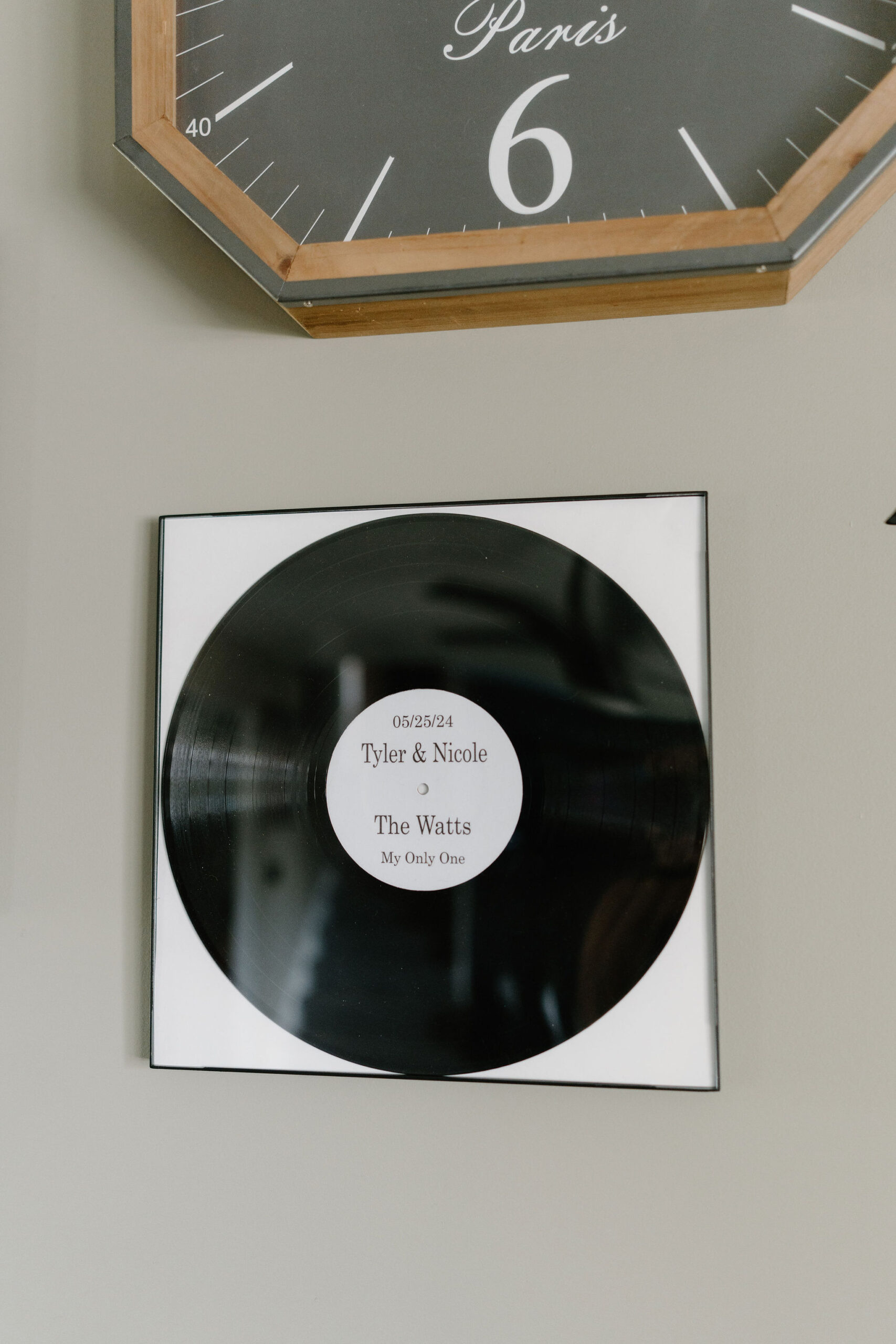 A custom record, framed and hung on a wall, reading "5/25/24 Tyler & Nicole, the Watts, My Only One".