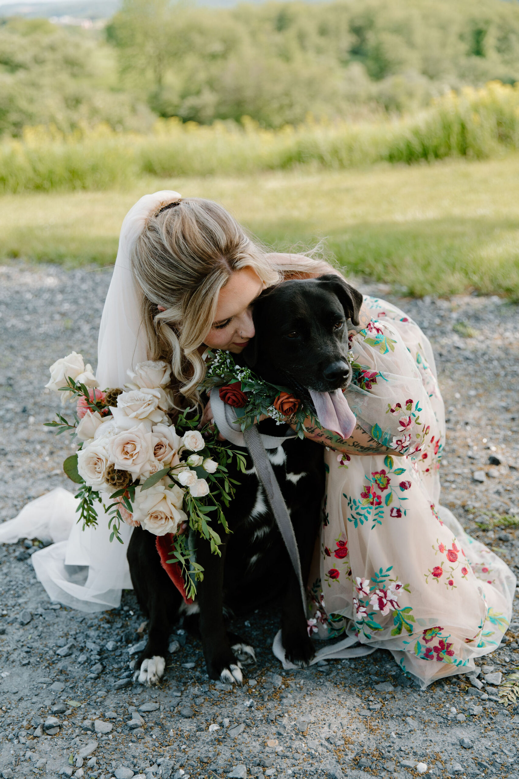 bride kneeling down and kissing her dog on the cheek