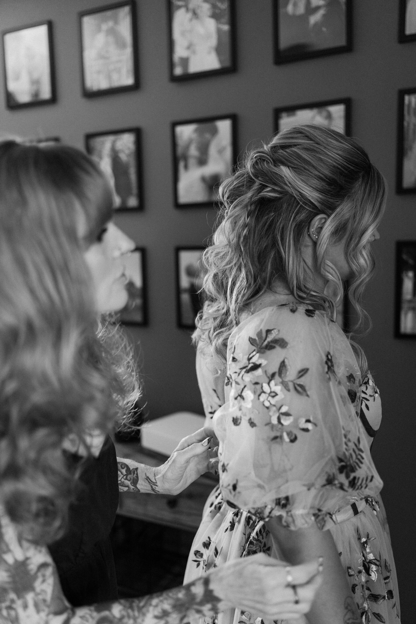 mother of the bride helping the bride get dressed and assessing her in the mirror, both heavily tattooed