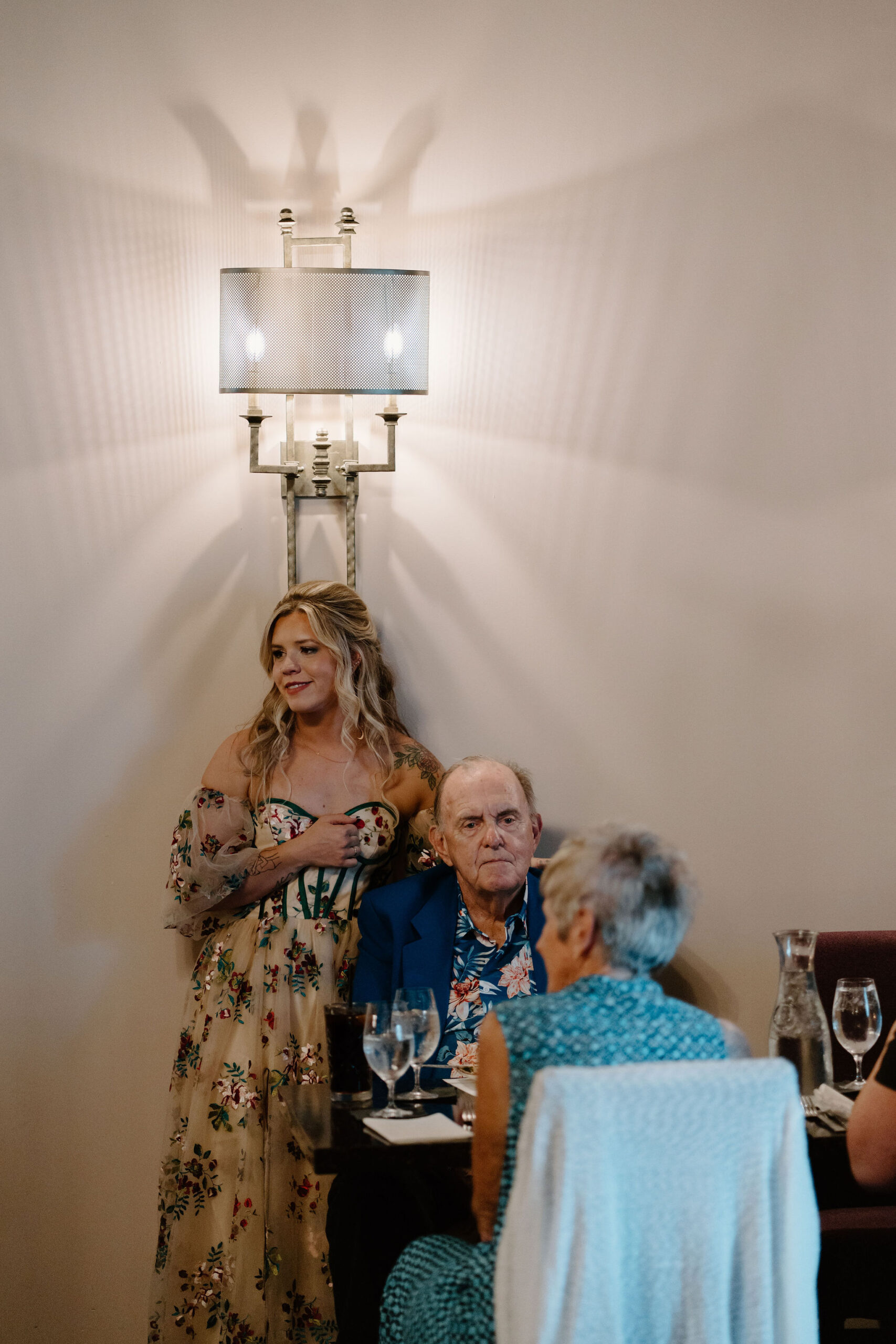 bride standing and smiling with her arm over her grandfather's shoulder during cocktail hour on their wedding day