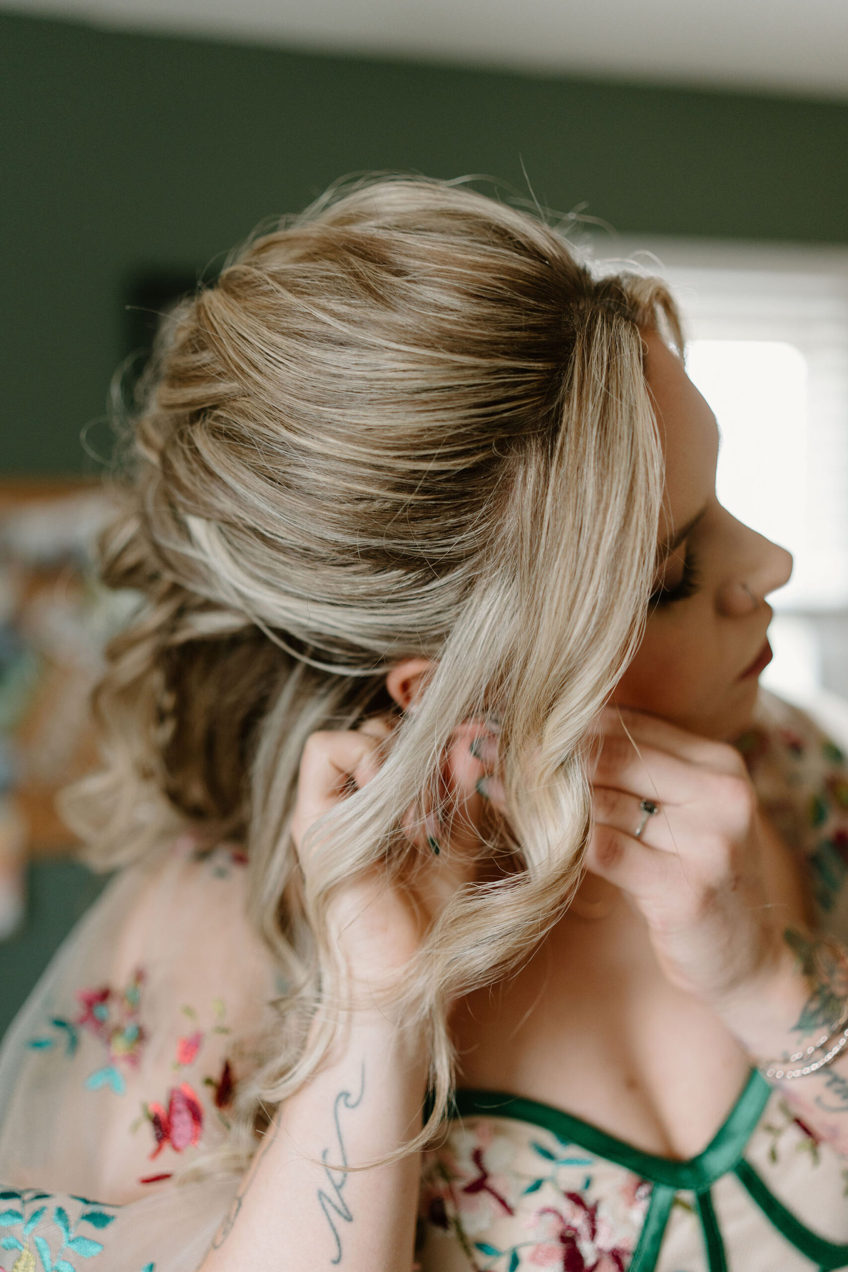 bride in a colorfully embroidered wedding dress putting in her earrings