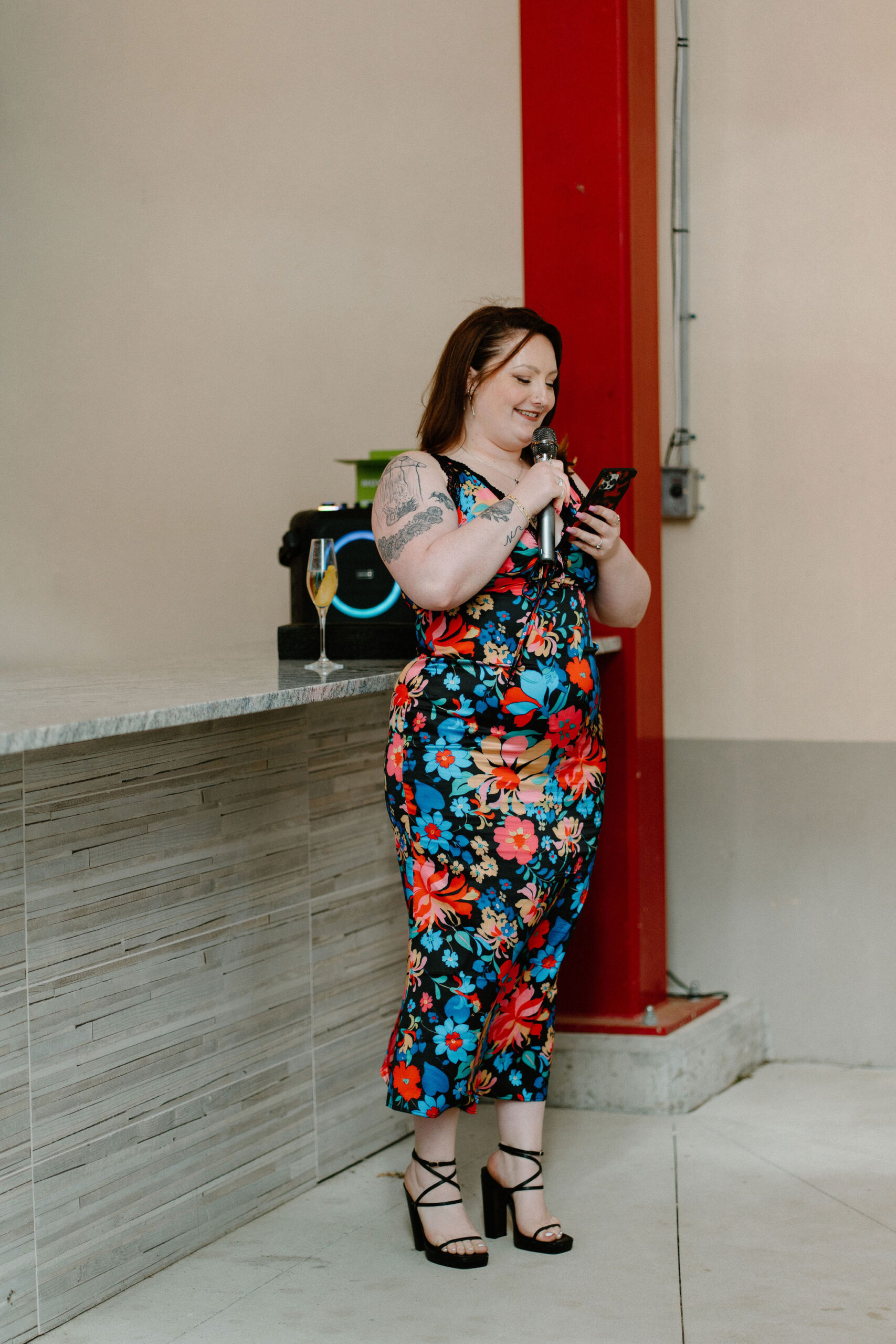 sister of the bride in a colorful dress smiling as she gives a speech