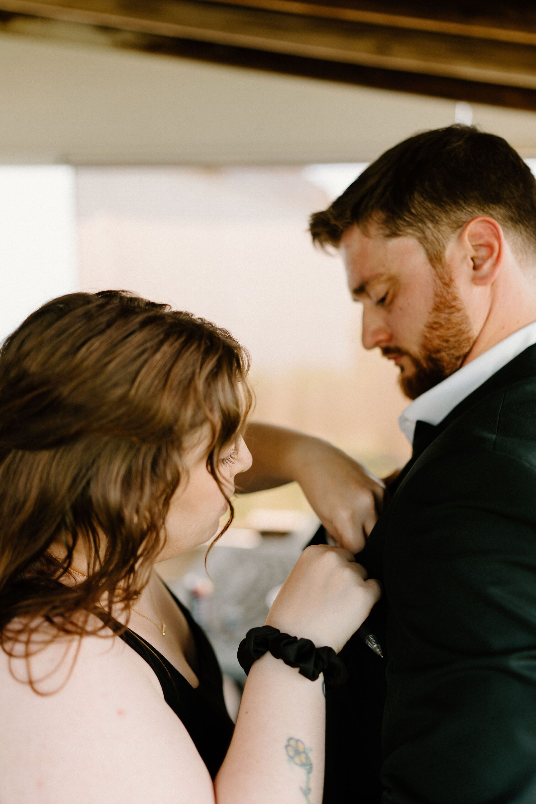 the groom having his boutonniere pinned on him by the wedding officiant