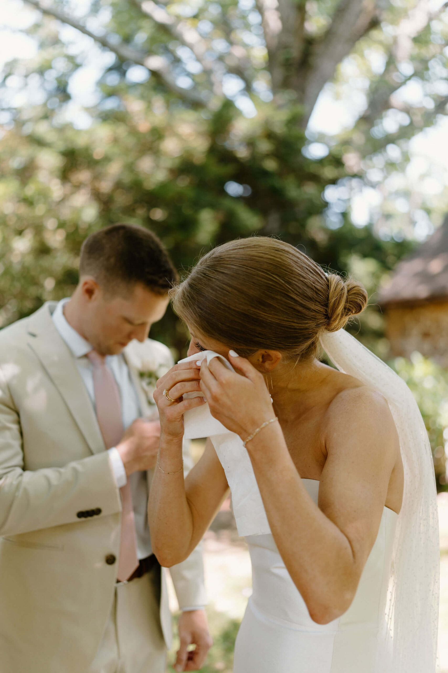 bride crying and dabbing her eyes with a tissue, while groom reaches inside his jacket for another tissue