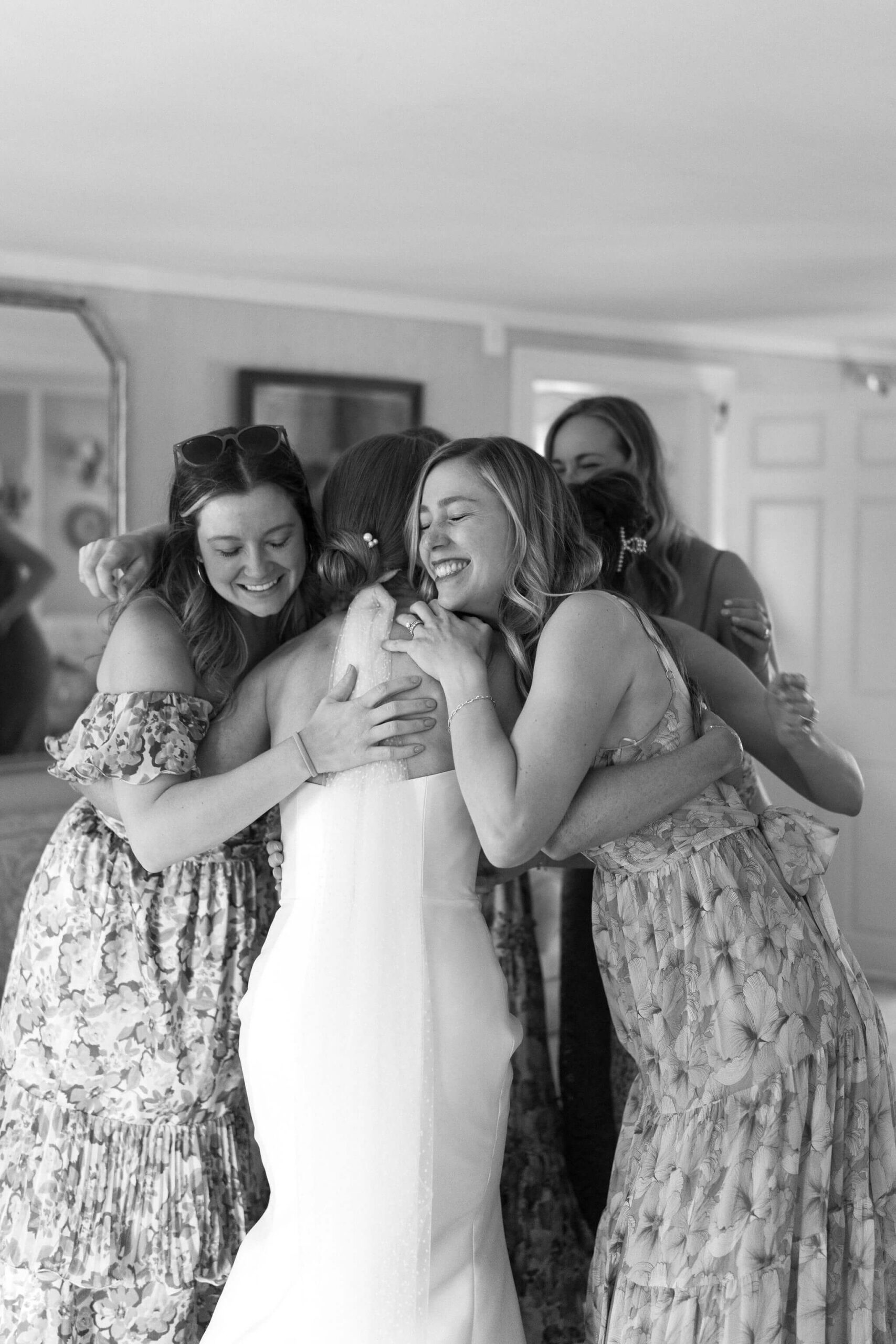bride in a white wedding gown hugging a group of friends, all wearing floral dresses