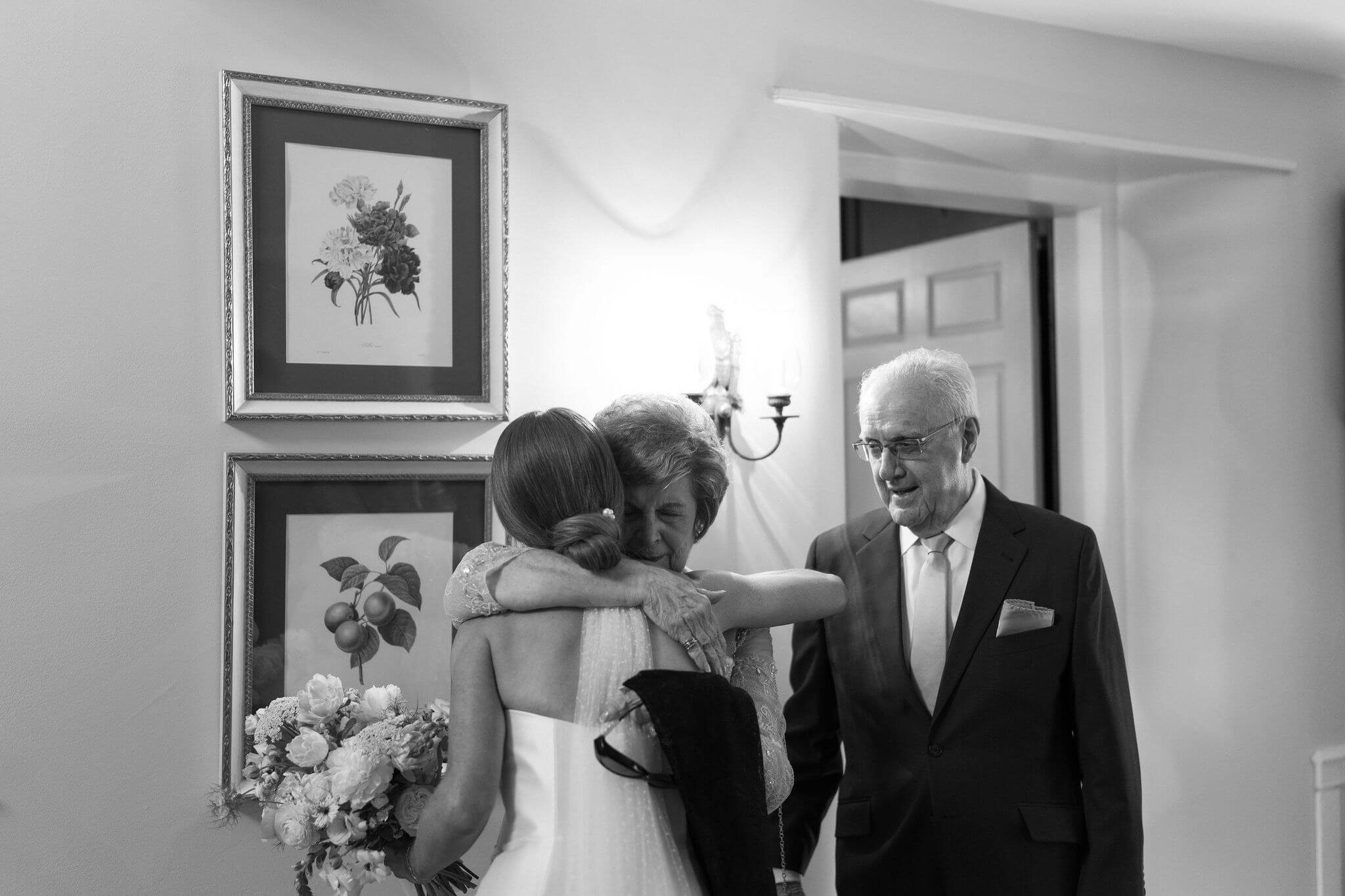 black and white image of bride hugging her grandmother, her grandfather next to them