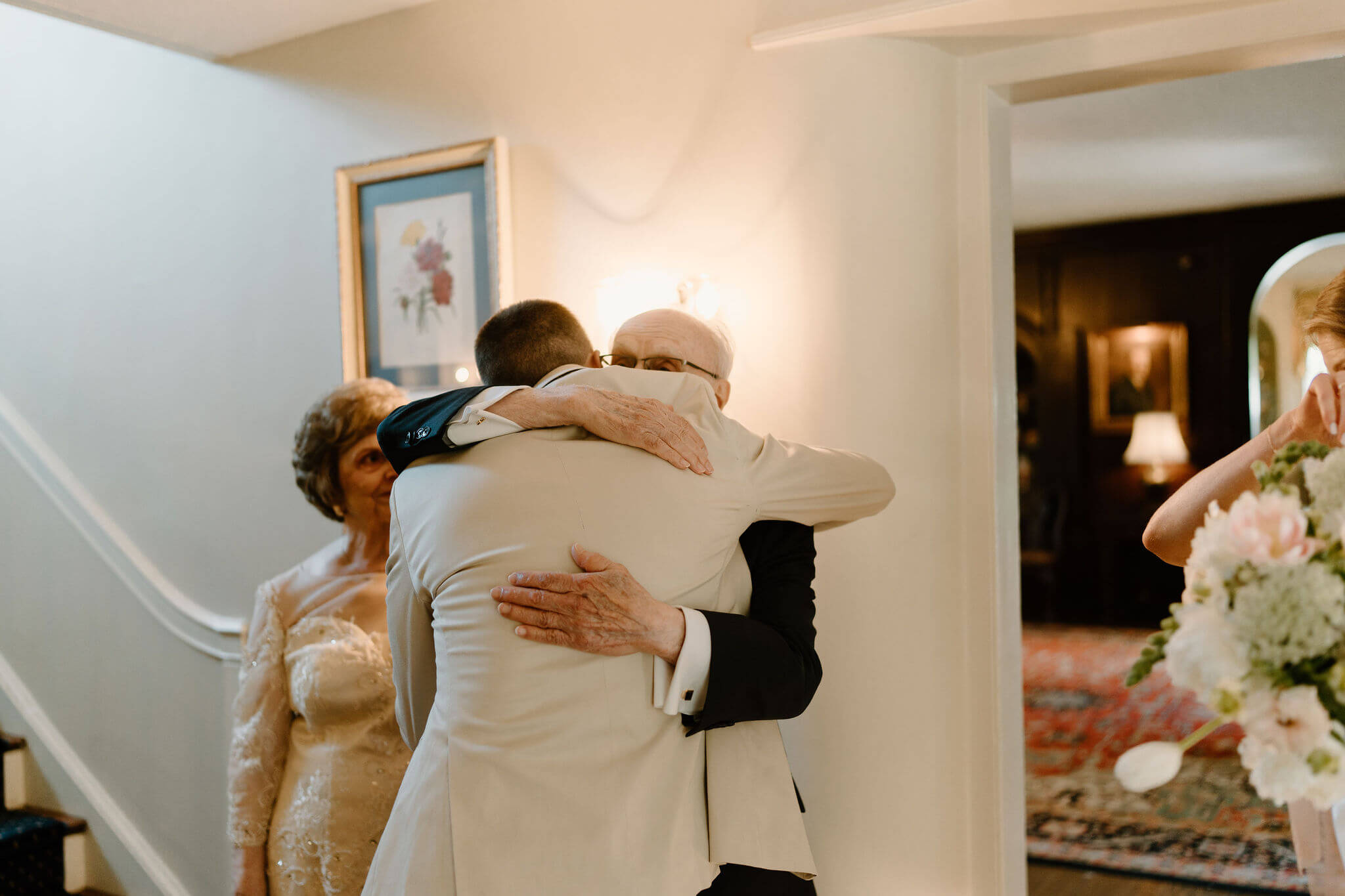 groom hugging bride's grandfather, her grandmother next to them