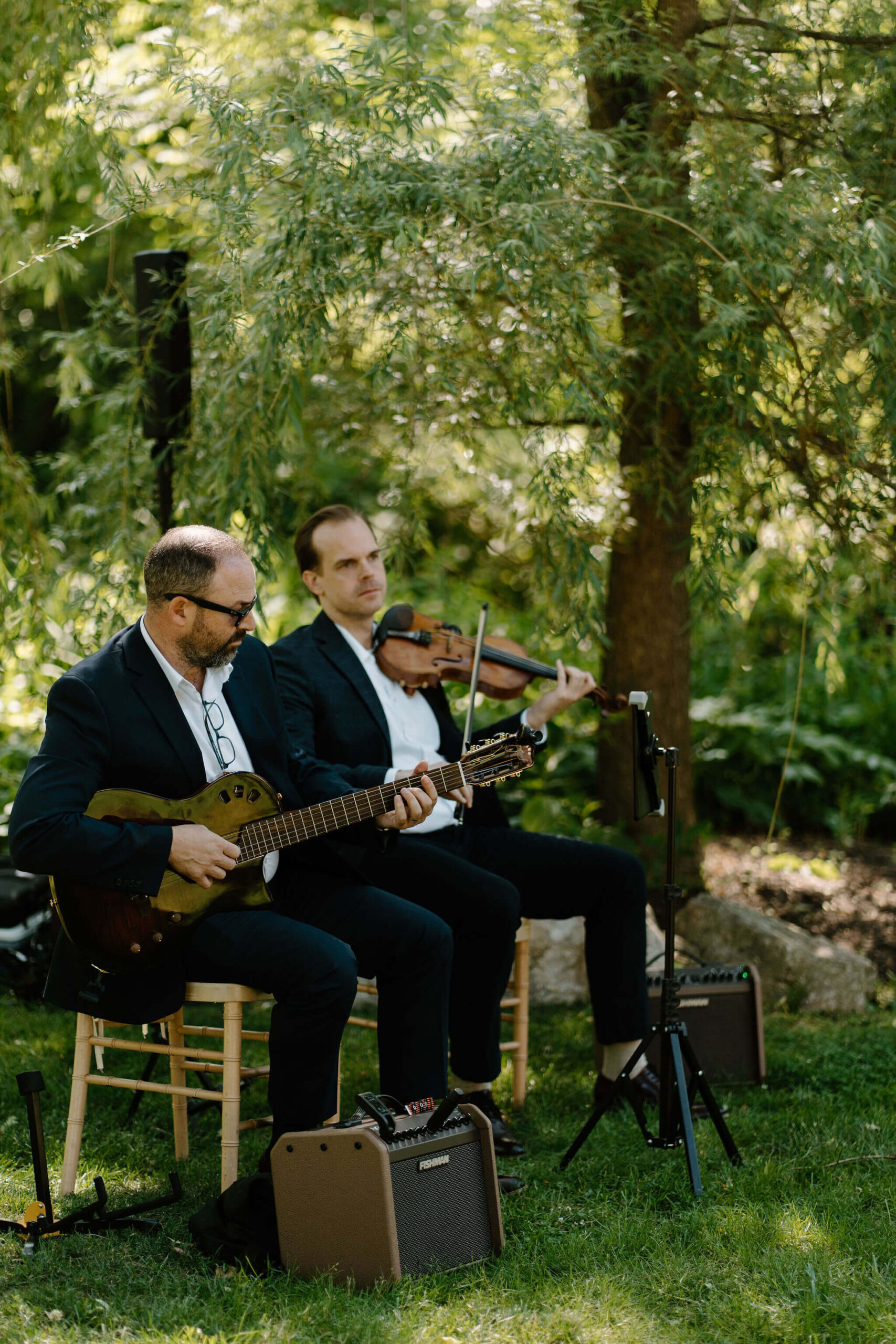 musicians for a wedding ceremony, sitting and playing a violin and guitar