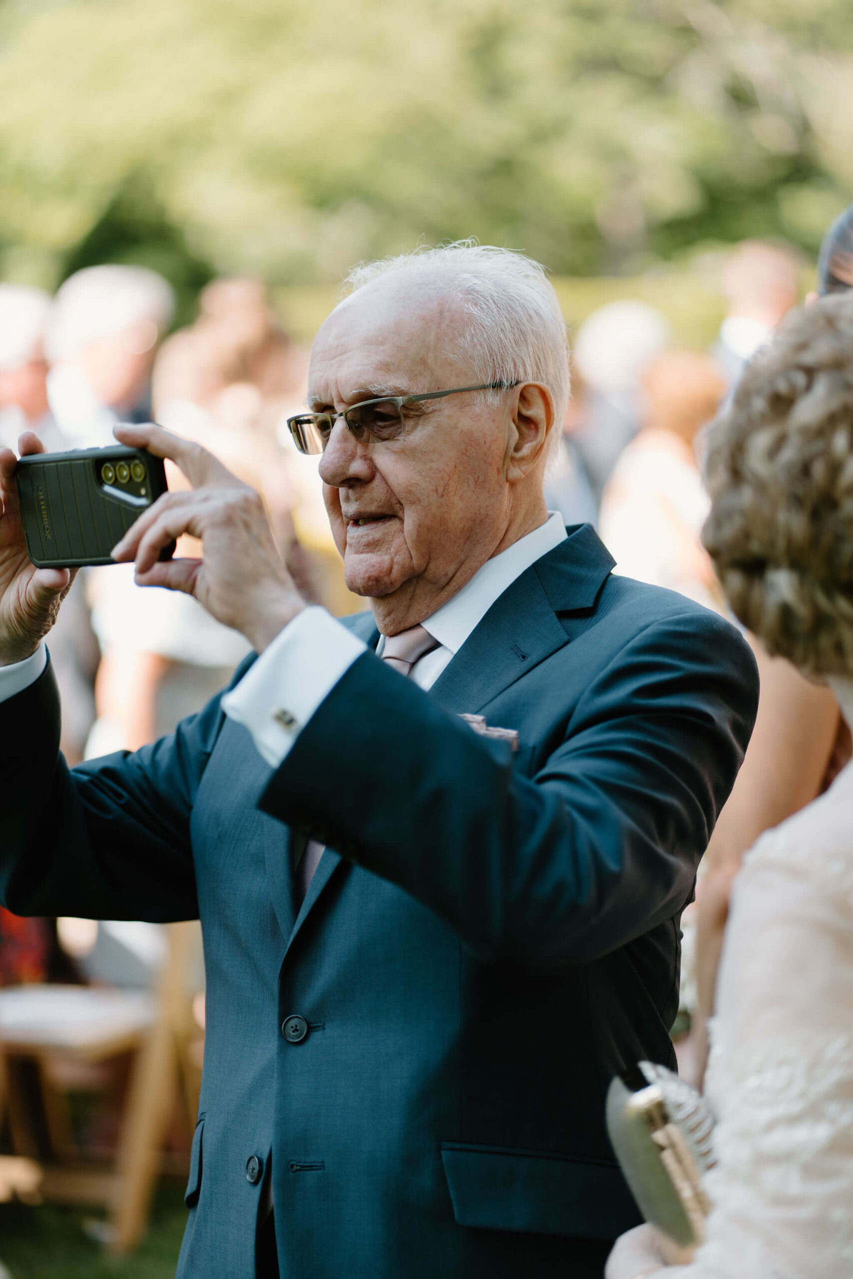 bride's grandfather taking an iphone photo of the wedding ceremony
