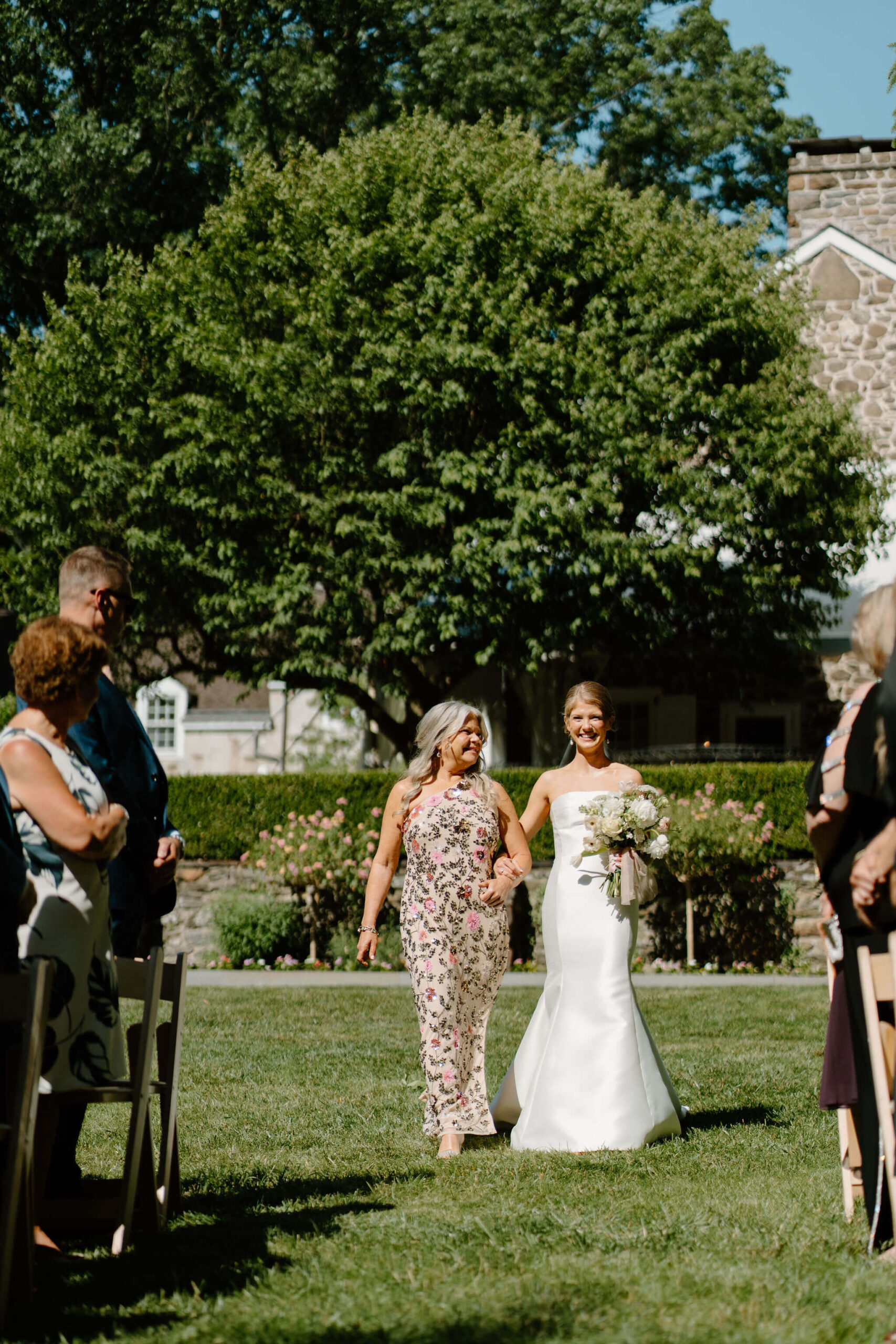 bride's mother looking at her as they walk down the aisle together for their wedding ceremony