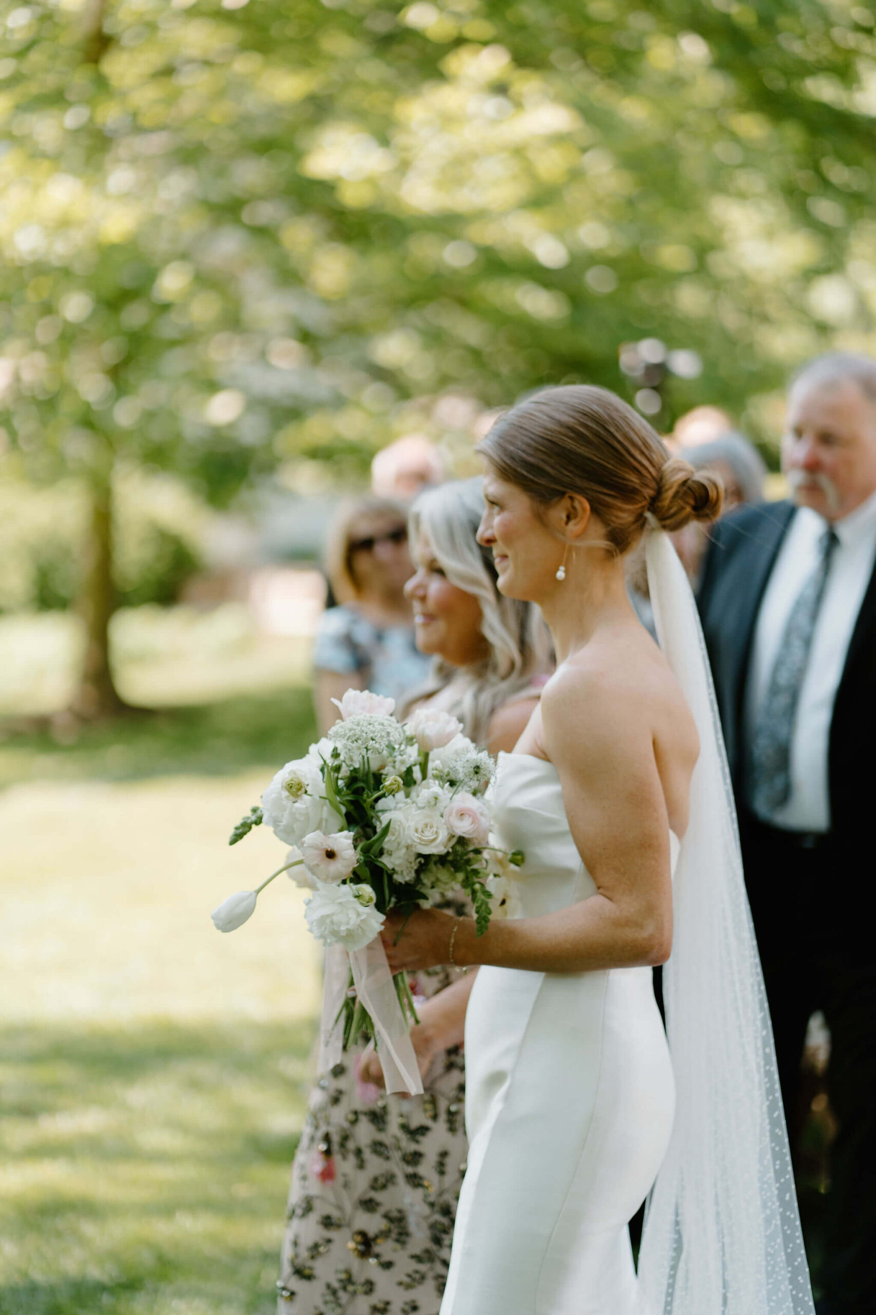 bride holding a bouquet, smiling at her groom as she walks down the aisle for their wedding ceremony
