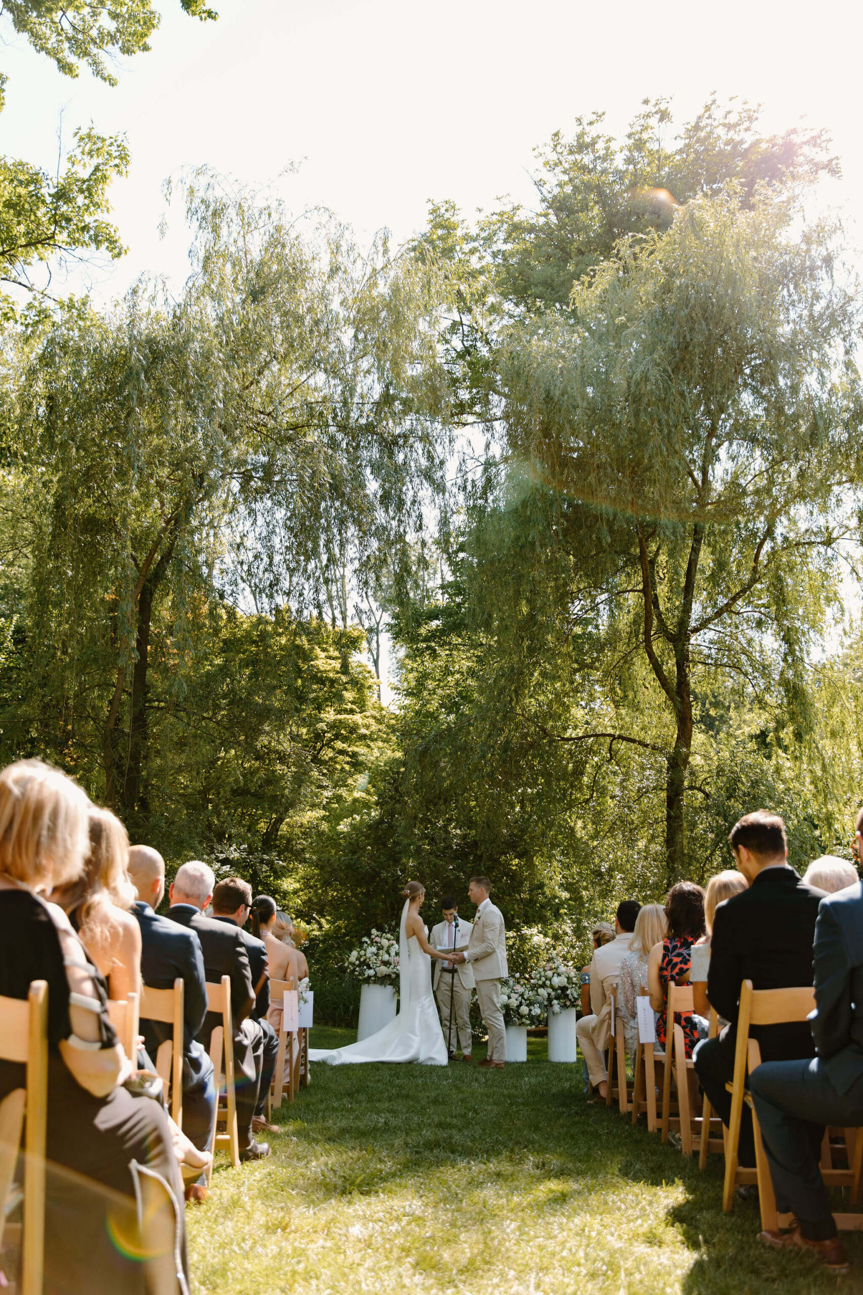 wide image looking straight down the aisle at a spring wedding ceremony, against a lush green background
