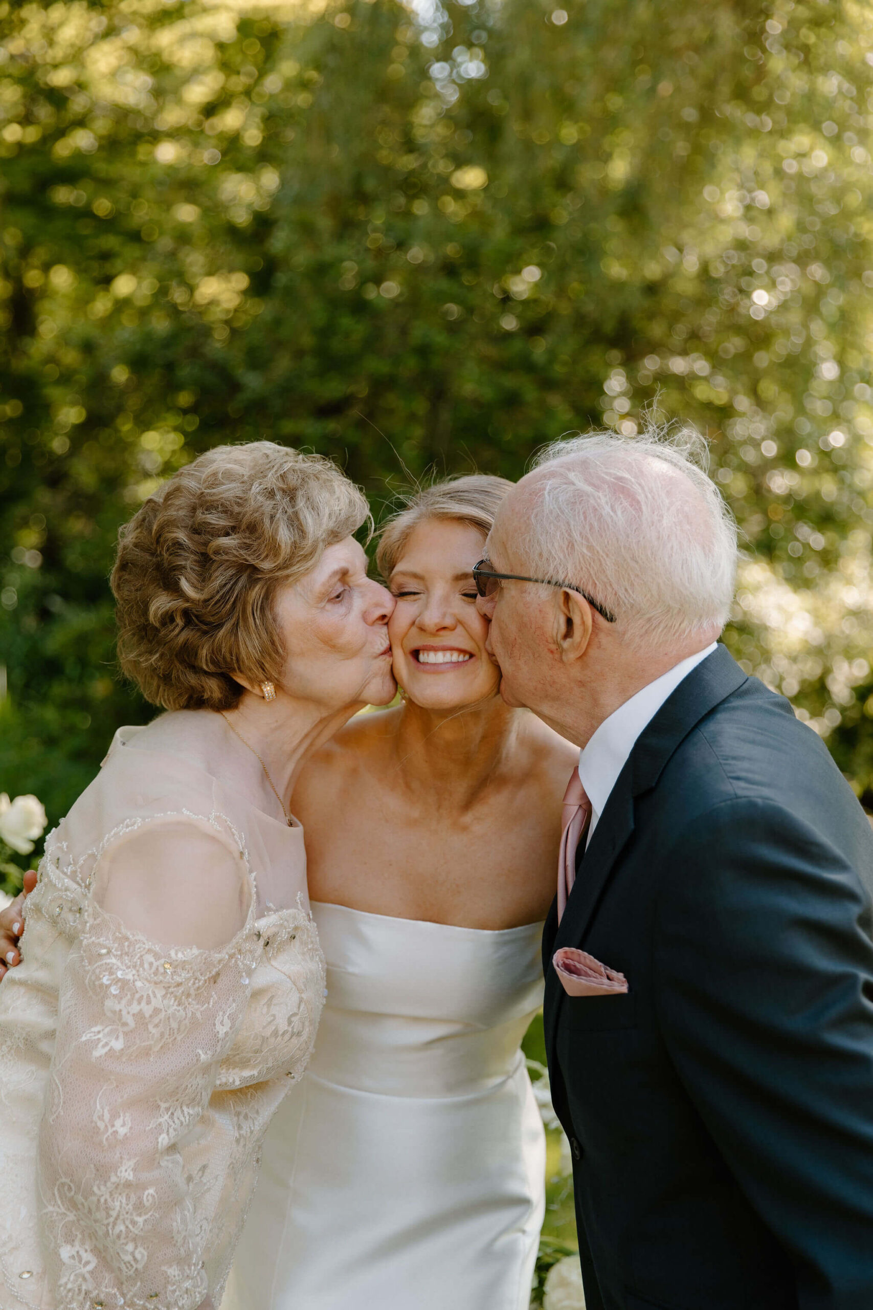 bride being kissed on the cheek by her grandmother and grandfather