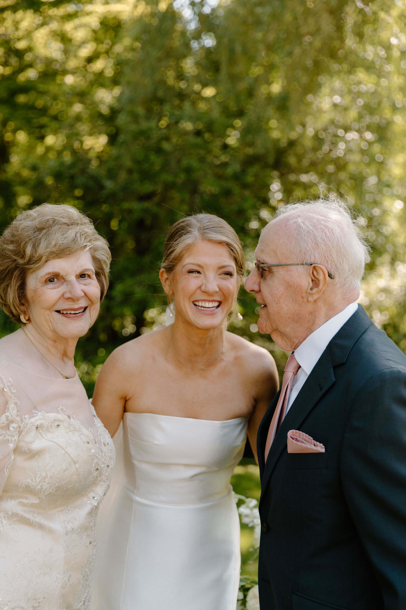 portrait of bride smiling and laughing with her grandmother and grandfather on her wedding day
