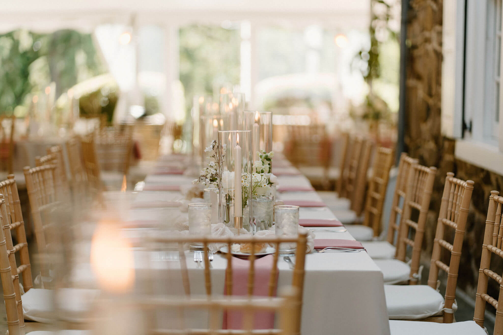 lit candlesticks inside a glass casing as a centerpiece of a long reception table