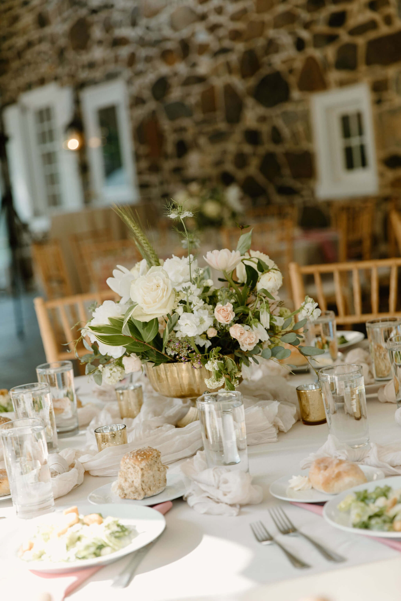 lush overflowing centerpiece with white and pink flowers on a round reception table