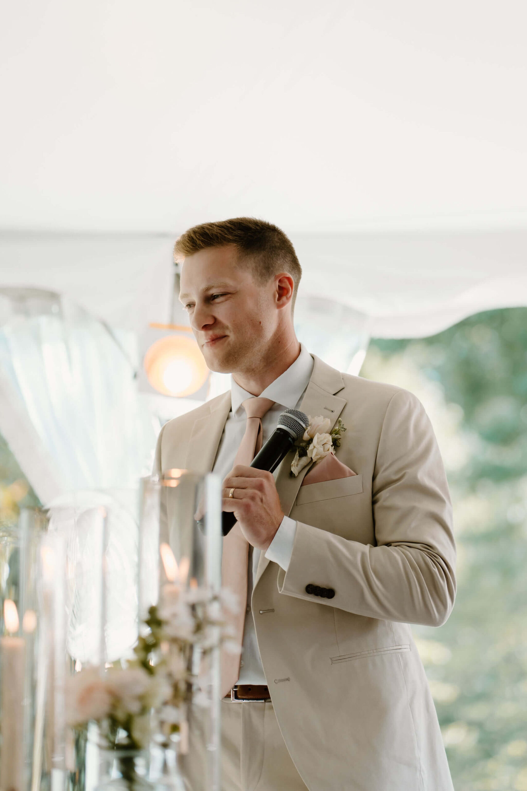 groom with a microphone, sharing a welcome speech with guests during wedding reception