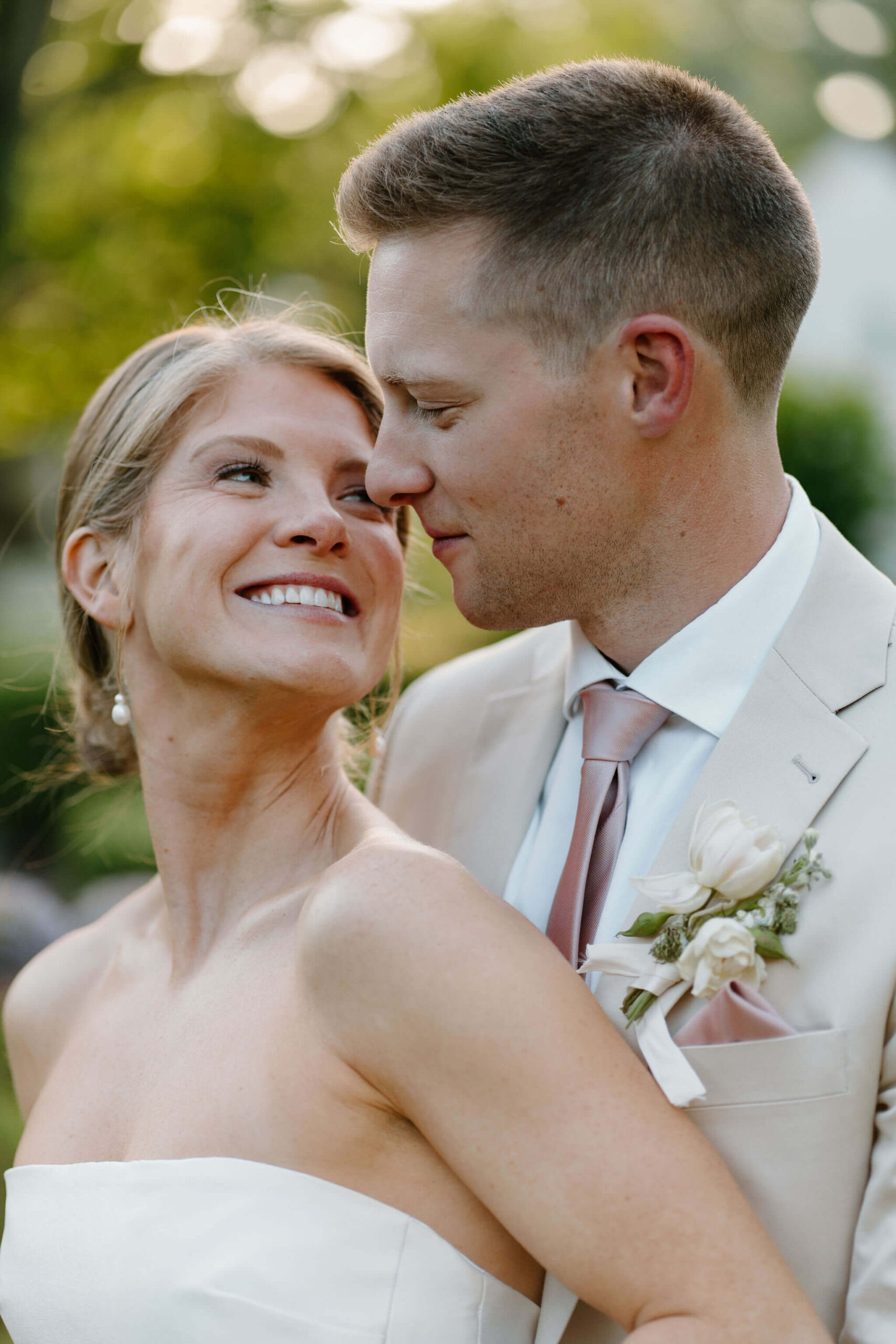 groom standing behind bride and smiling at her, as she smiles back at him
