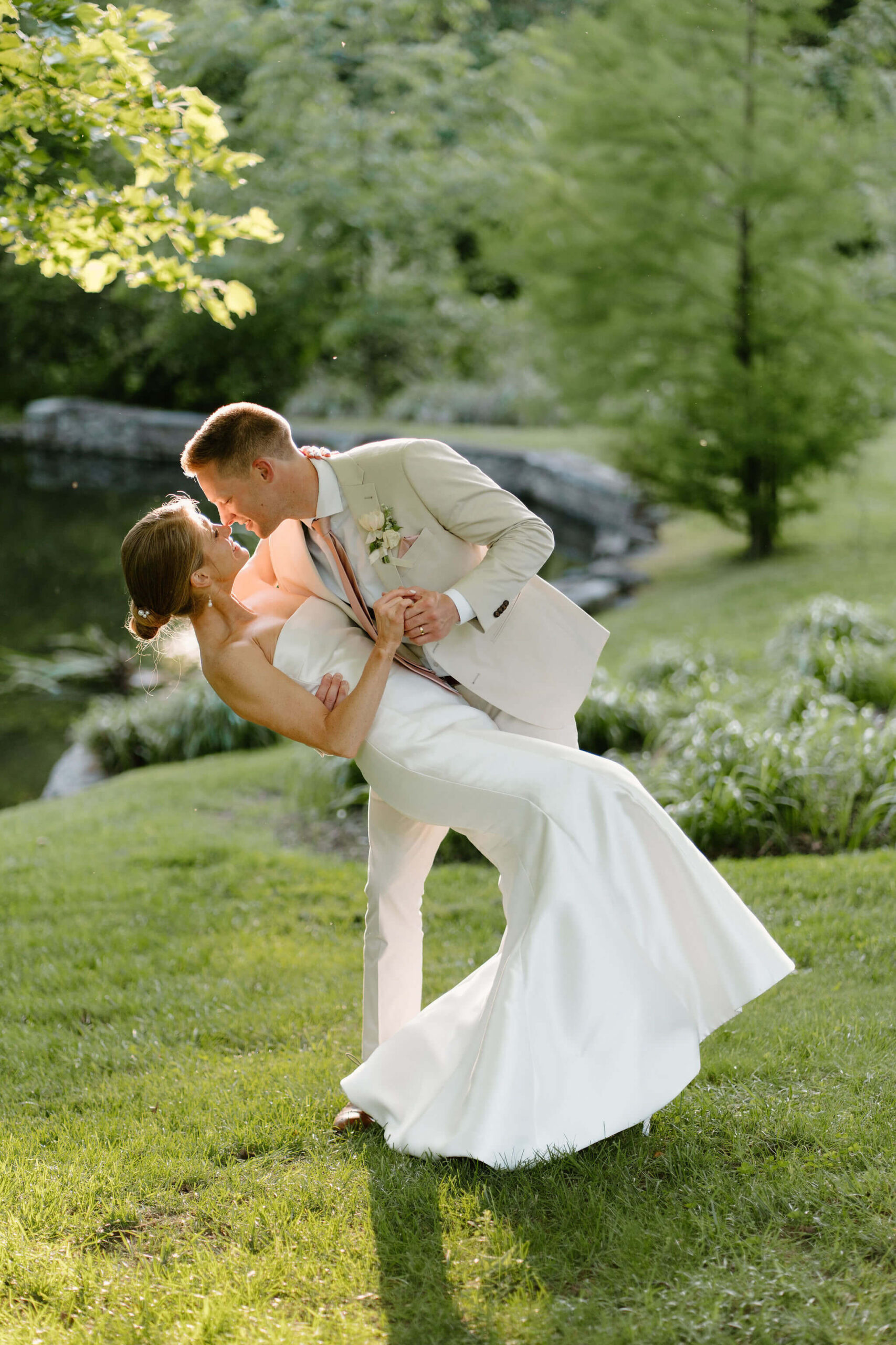 groom dipping bride in front of a lush green background