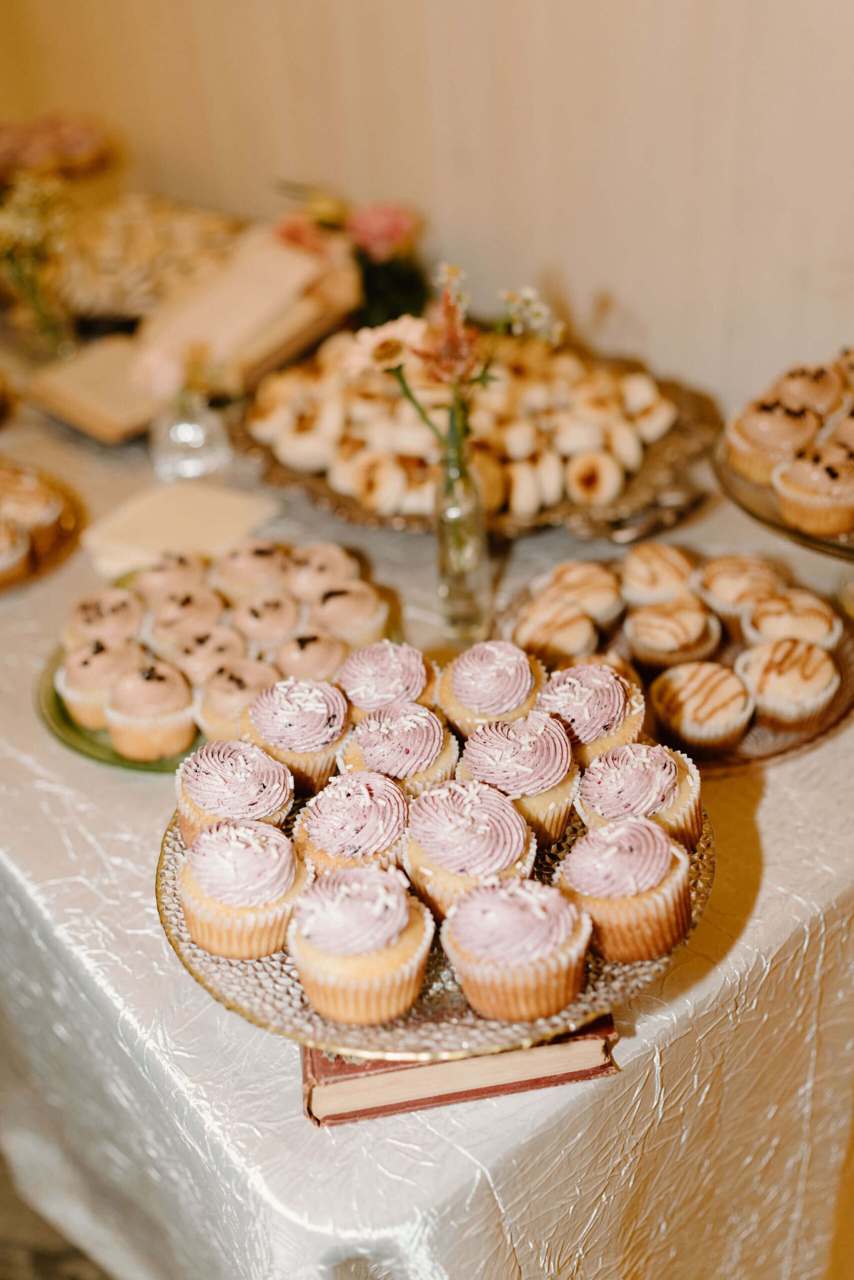 a tray of beautifully iced cupcakes set up on a dessert table overflowing with single-serving desserts