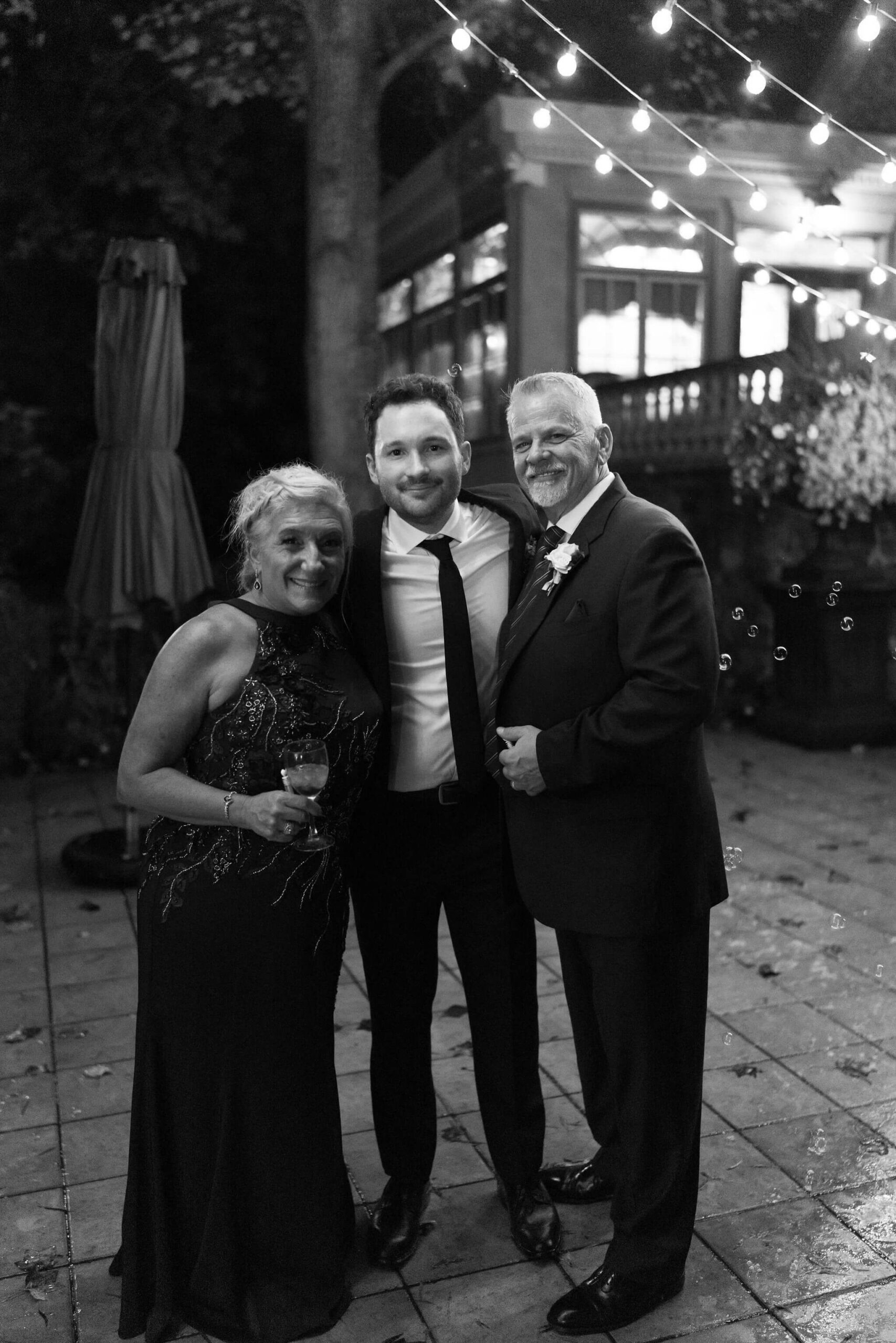 groom with mother and stepfather smiling at the camera
