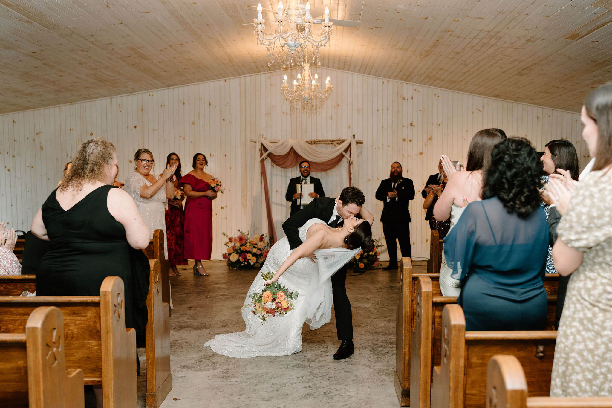 groom dipping bride in the middle of the aisle after their wedding ceremony