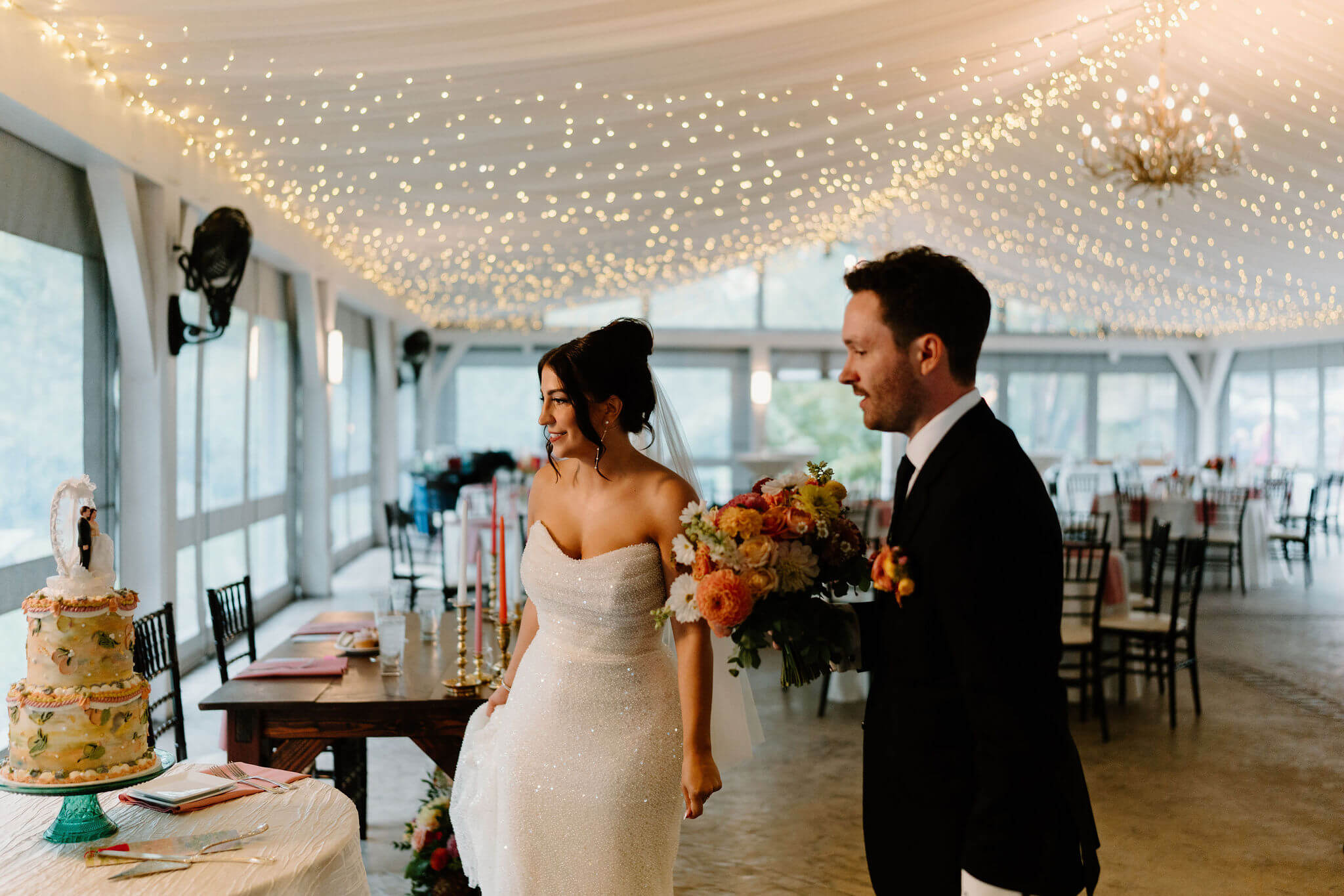 bride and groom in their reception space, admiring their colorful wedding cake