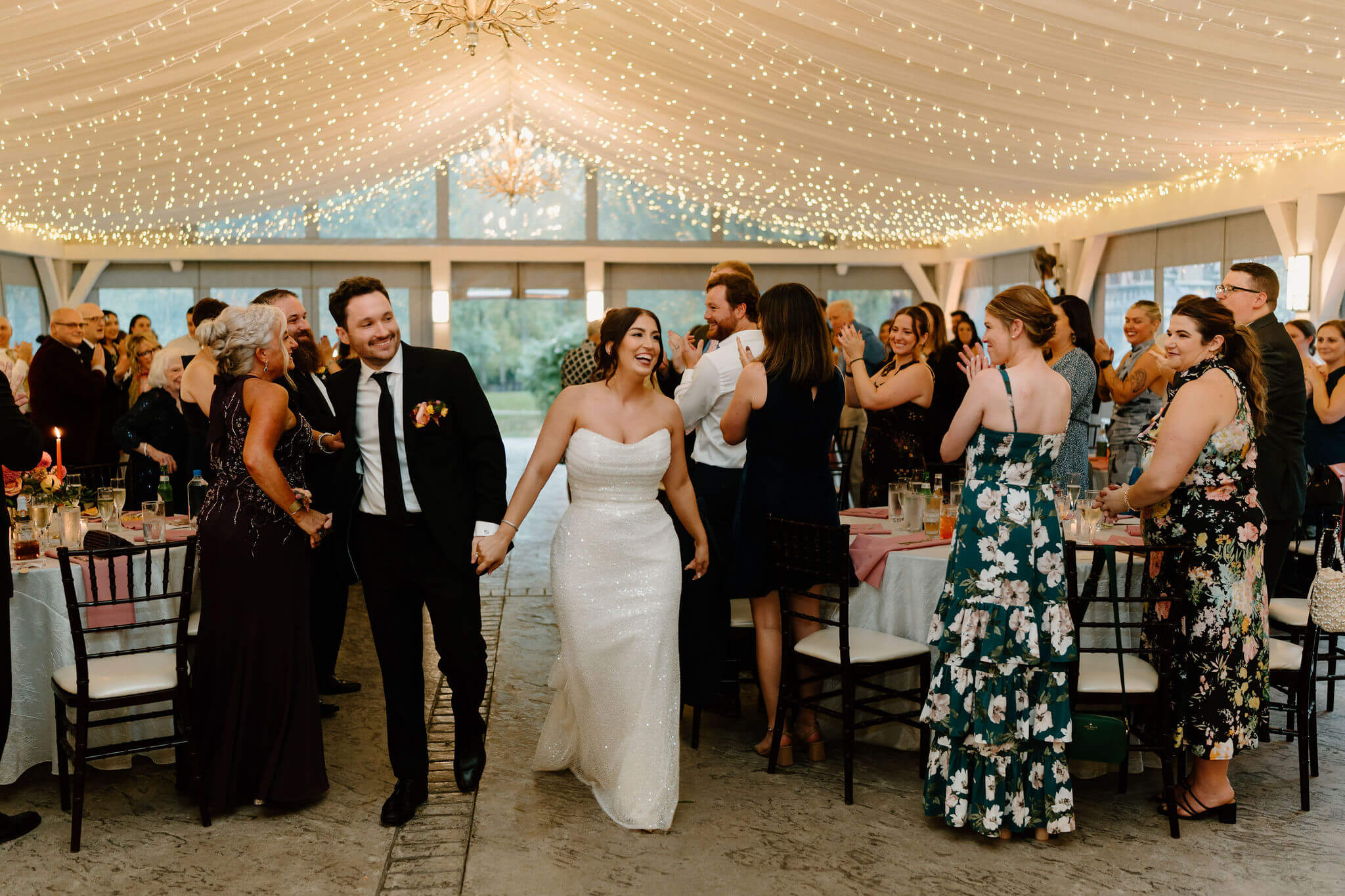 bride and groom entering their wedding reception, guests standing and applauding