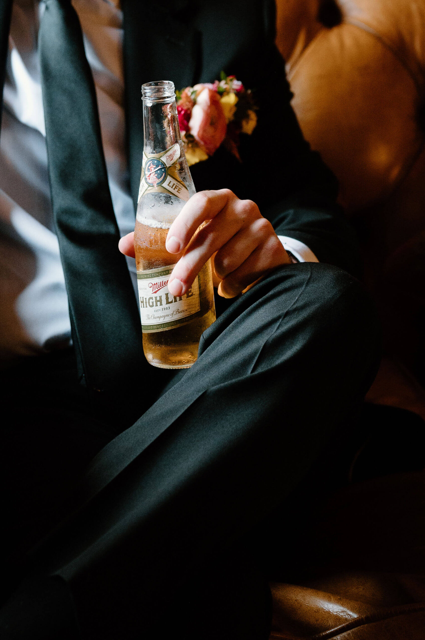 close up image of groom's hand holding a Miller High Life