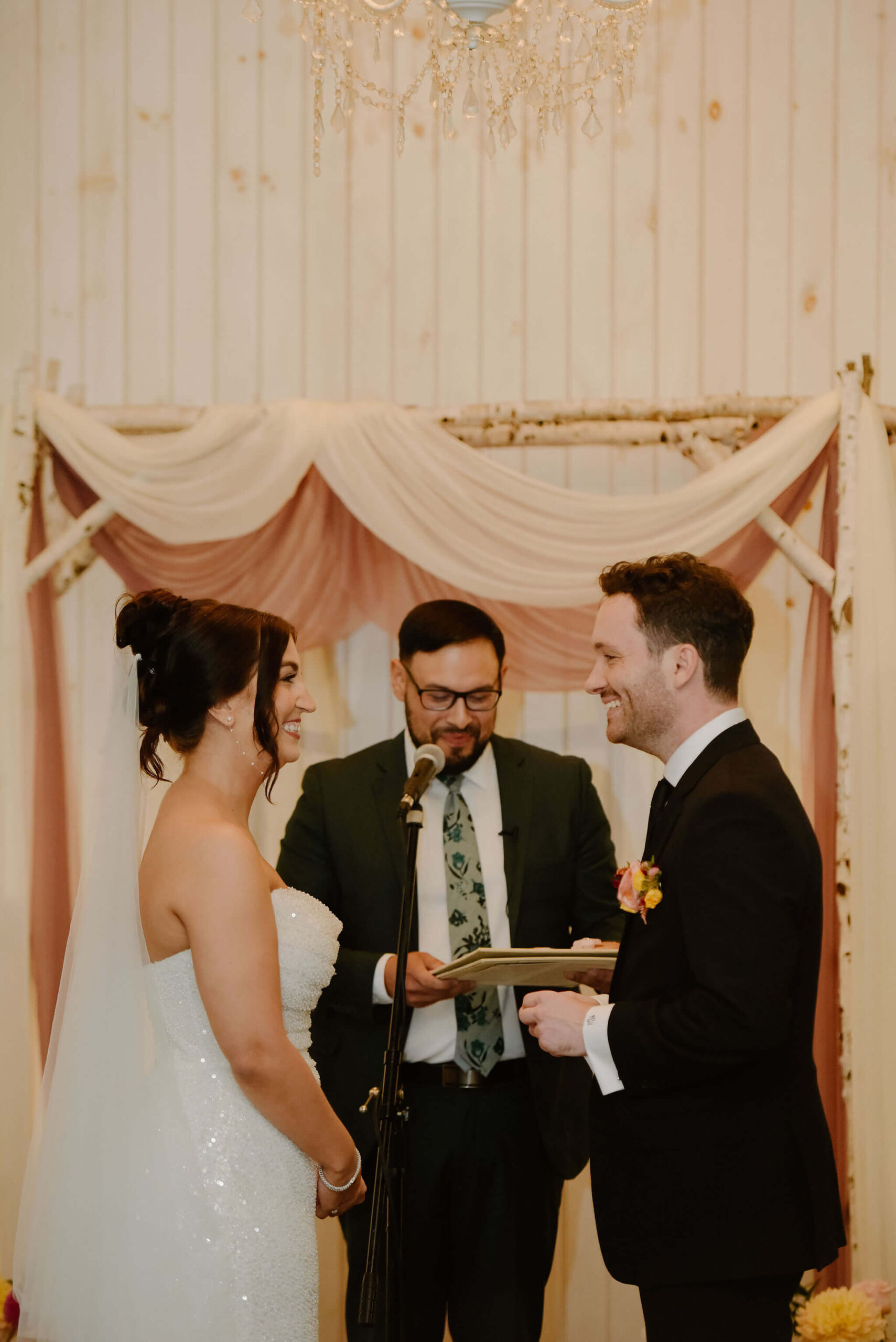 bride and groom smiling at each other during their wedding ceremony