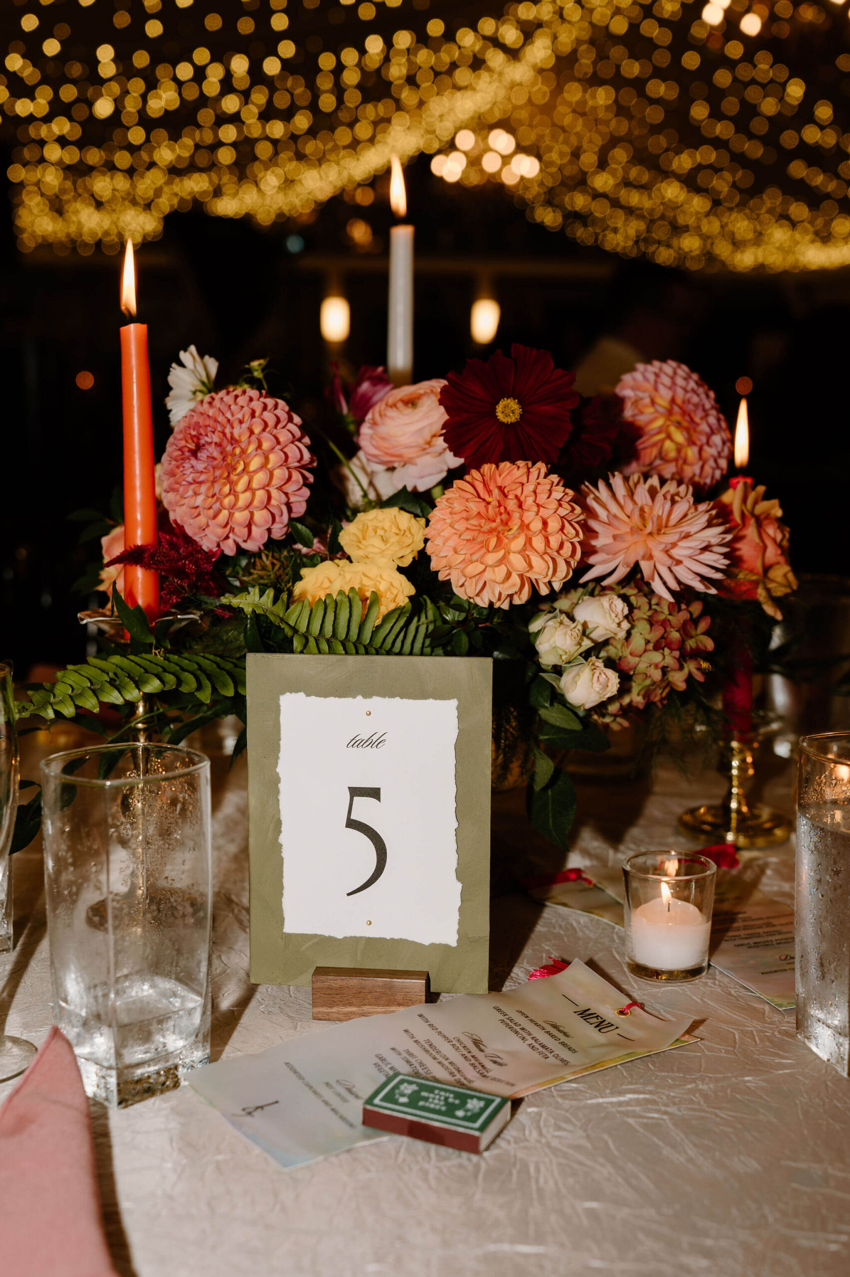 colorful floral arrangement and table number, complete with colorful tall candlesticks at a DIY wedding