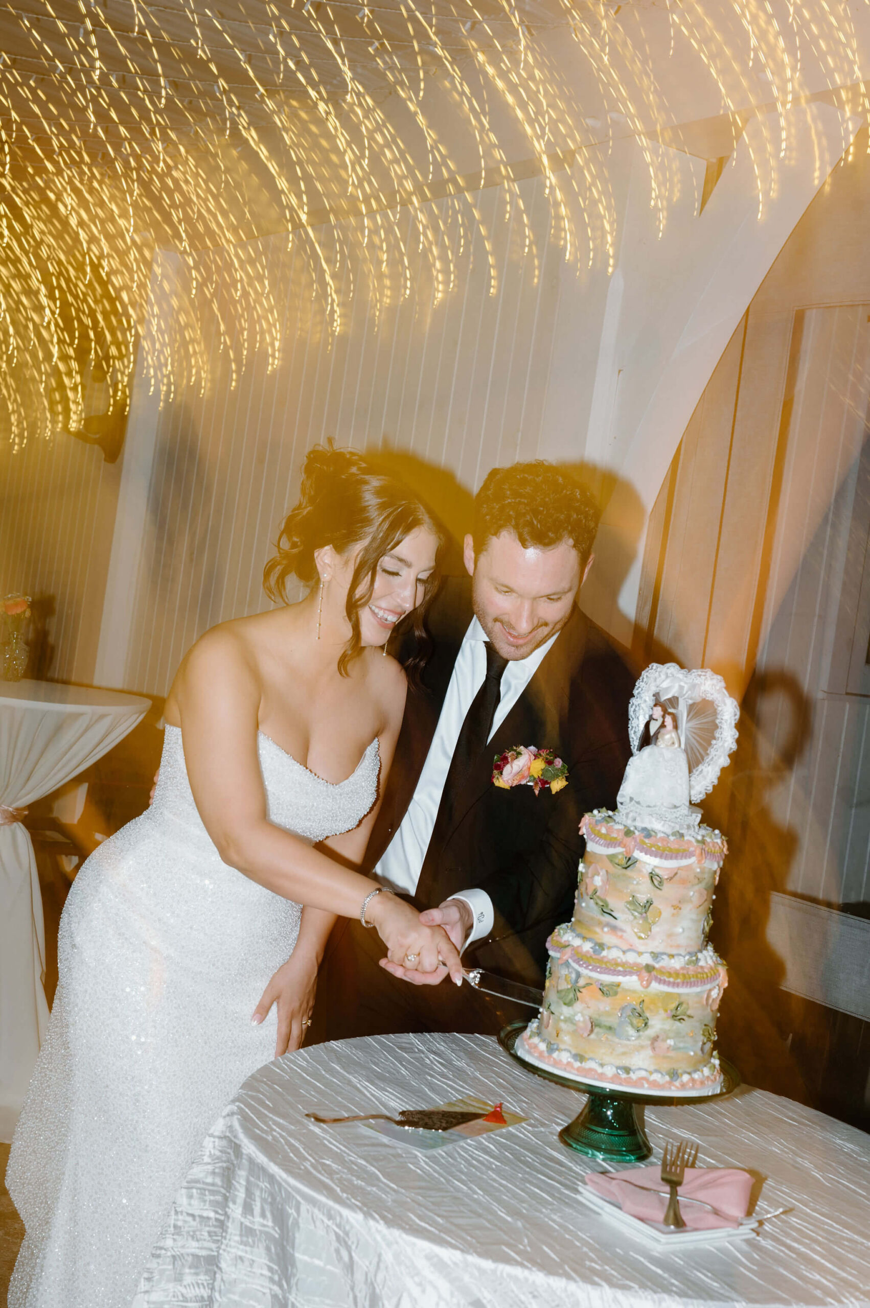 shutter drag image of bride and groom cutting colorful vintage wedding cake