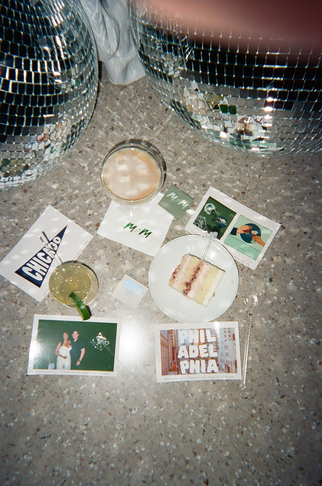"late-night flat lay" consisting of an espresso martini, a piece of cake, a mule, several post cards, a matchbook, and disco balls