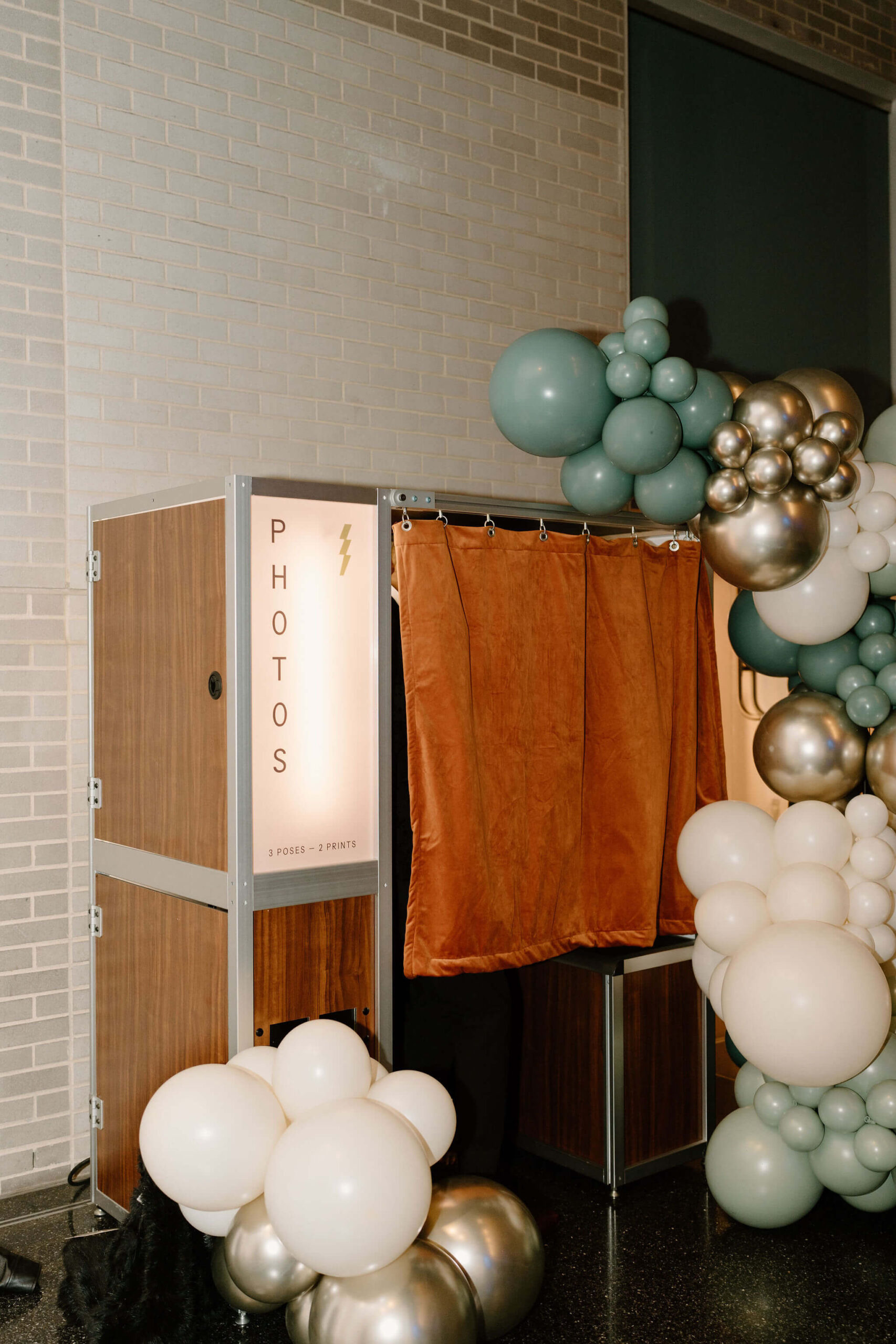 vintage-style photobooth with an orange curtain, surrounded by a large balloon installation