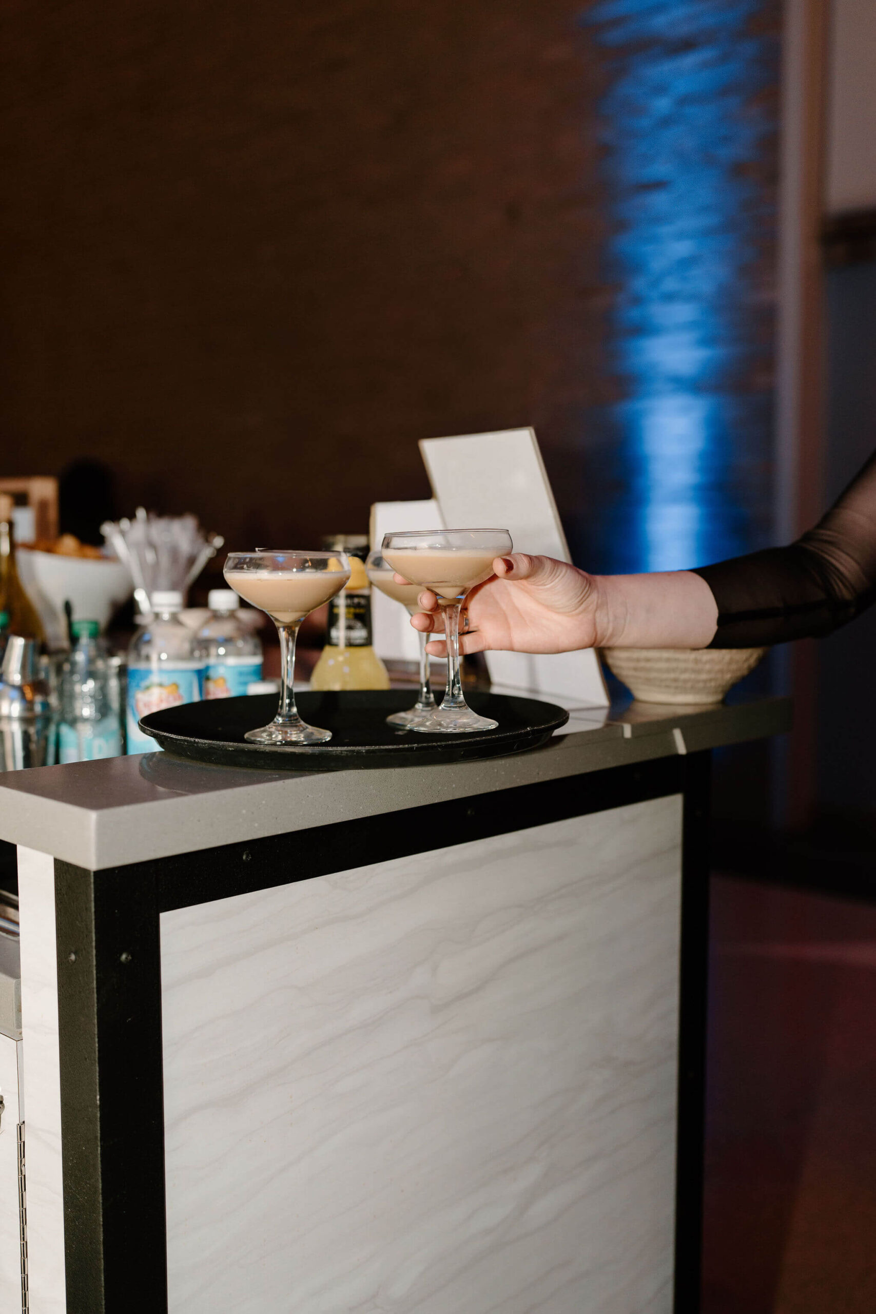 close-up of a guest's hand reaching to select an espresso martini from a tray